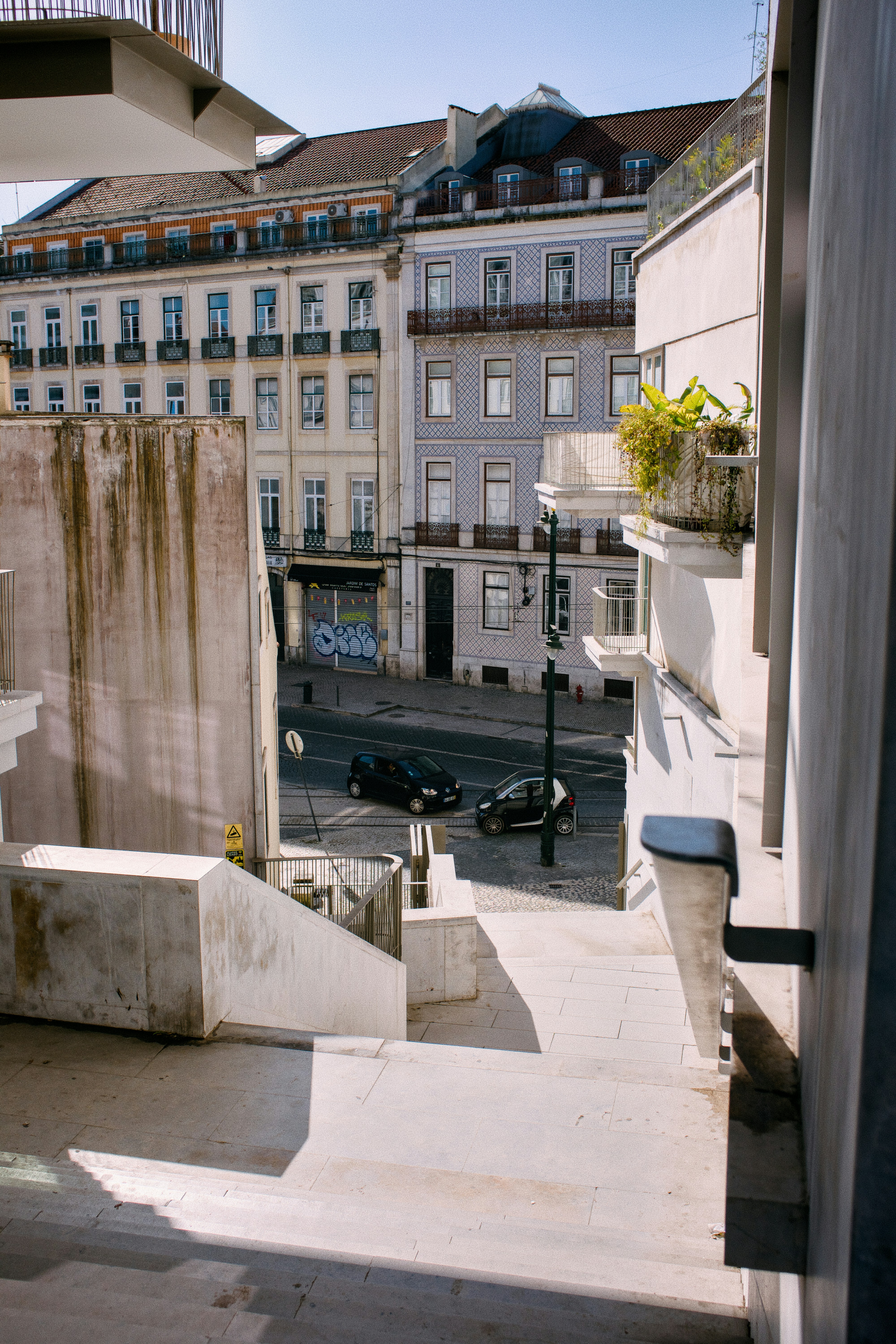 View from stairs looking down at a street with cars.