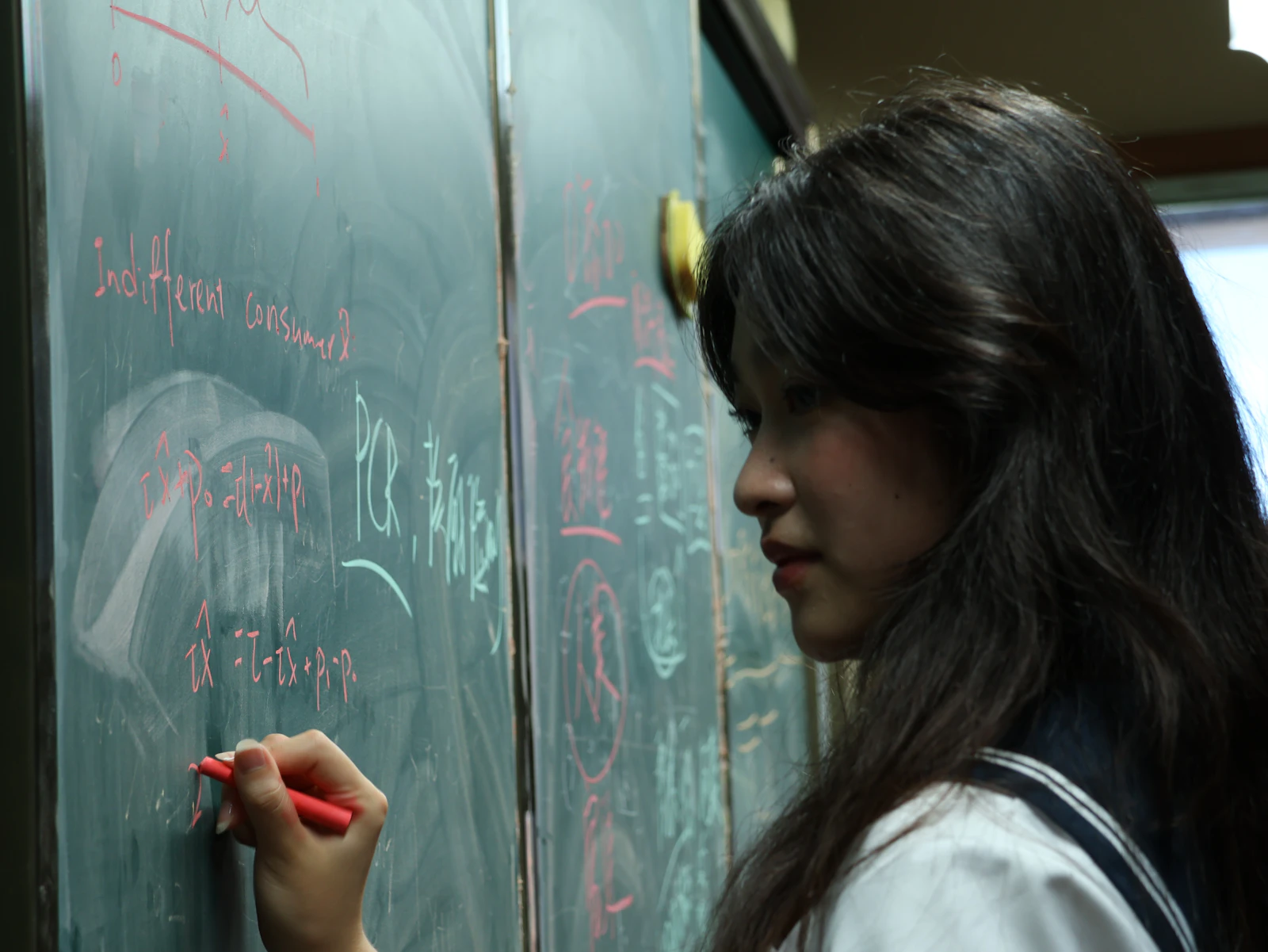 Student solving a problem on the blackboard in front of the class