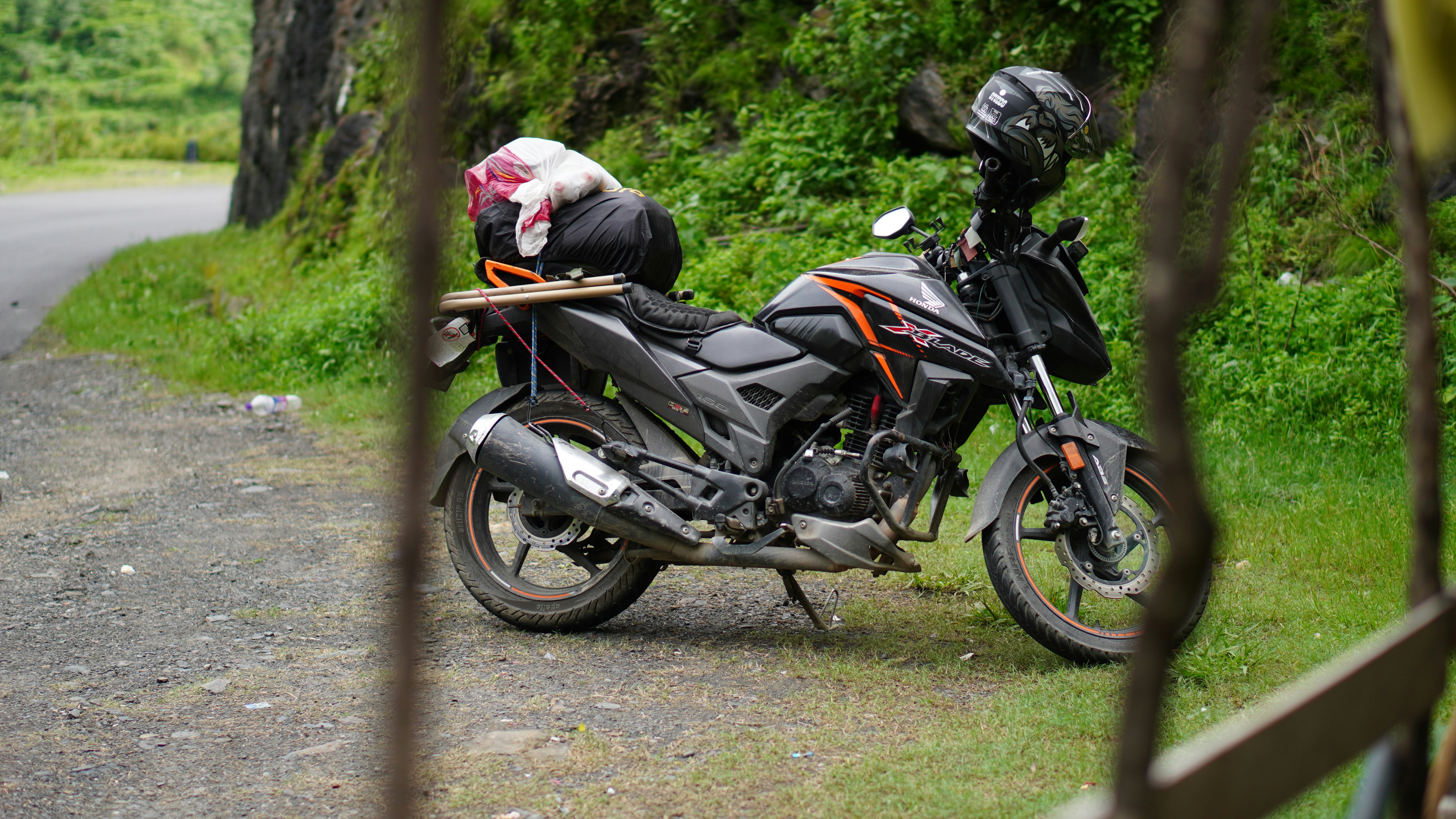 A motorcycle parked on a dirt road with luggage.