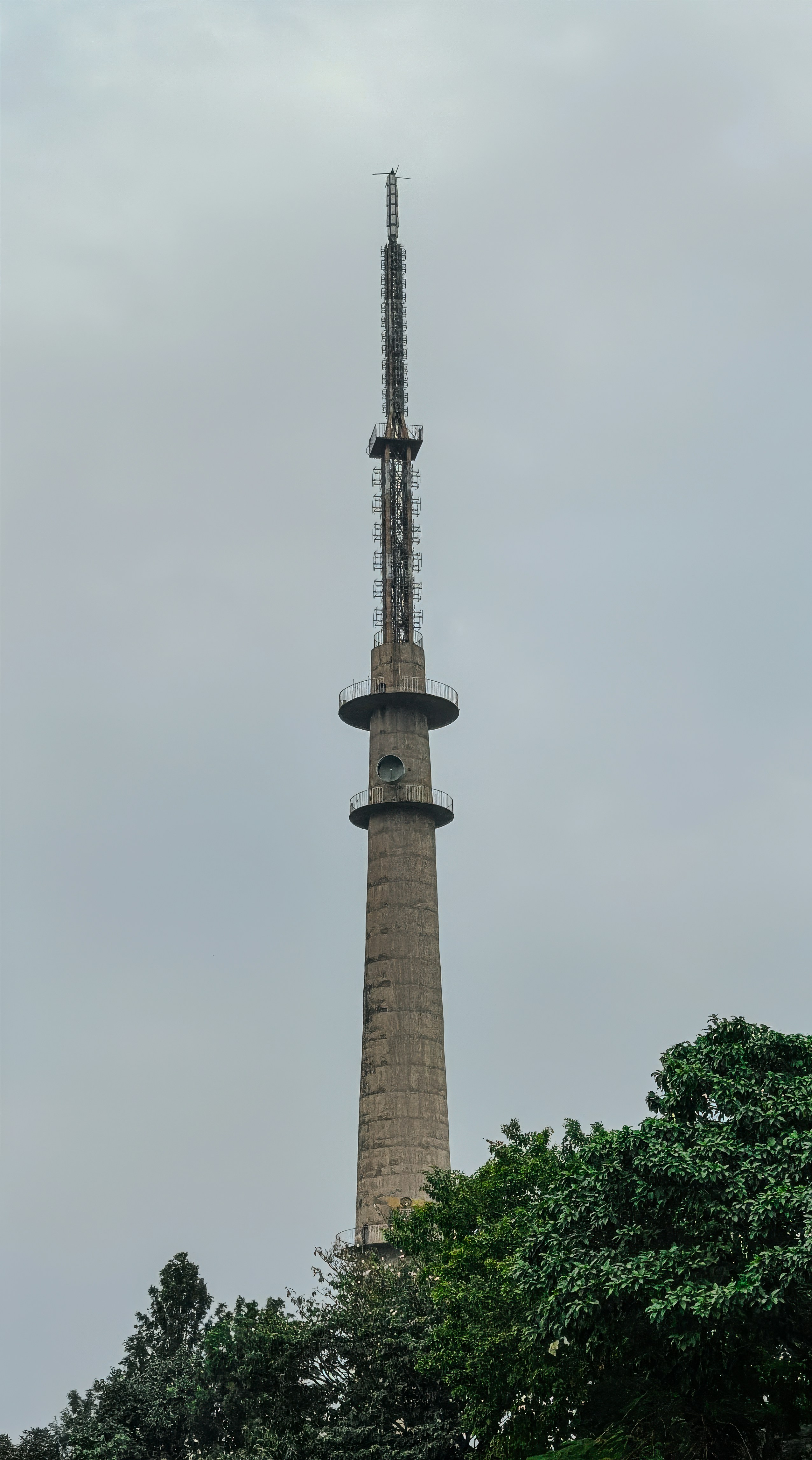 Alta torre de hormigón con antena contra cielo nublado
