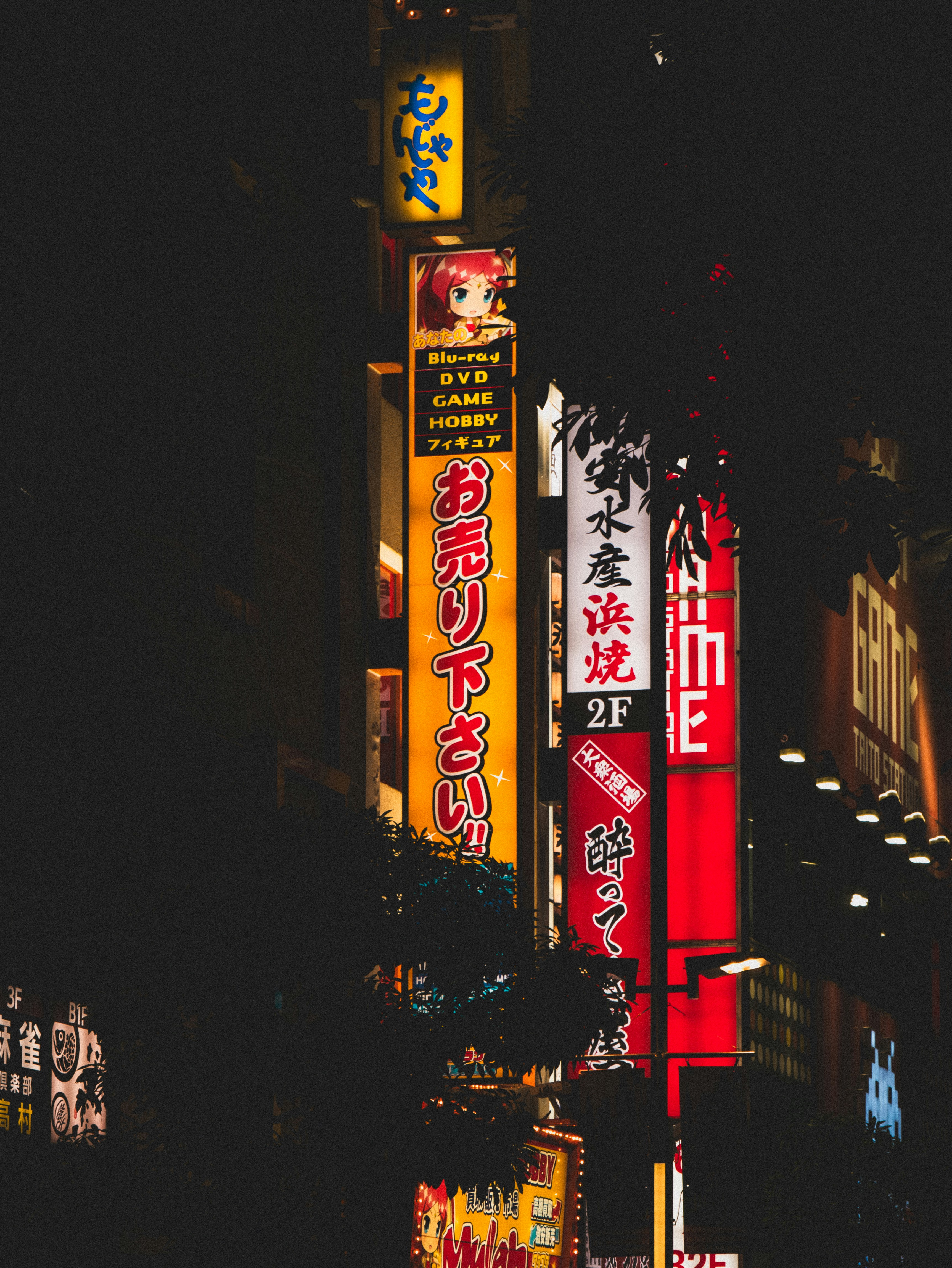 Bright neon signs illuminate a dark city street at night.