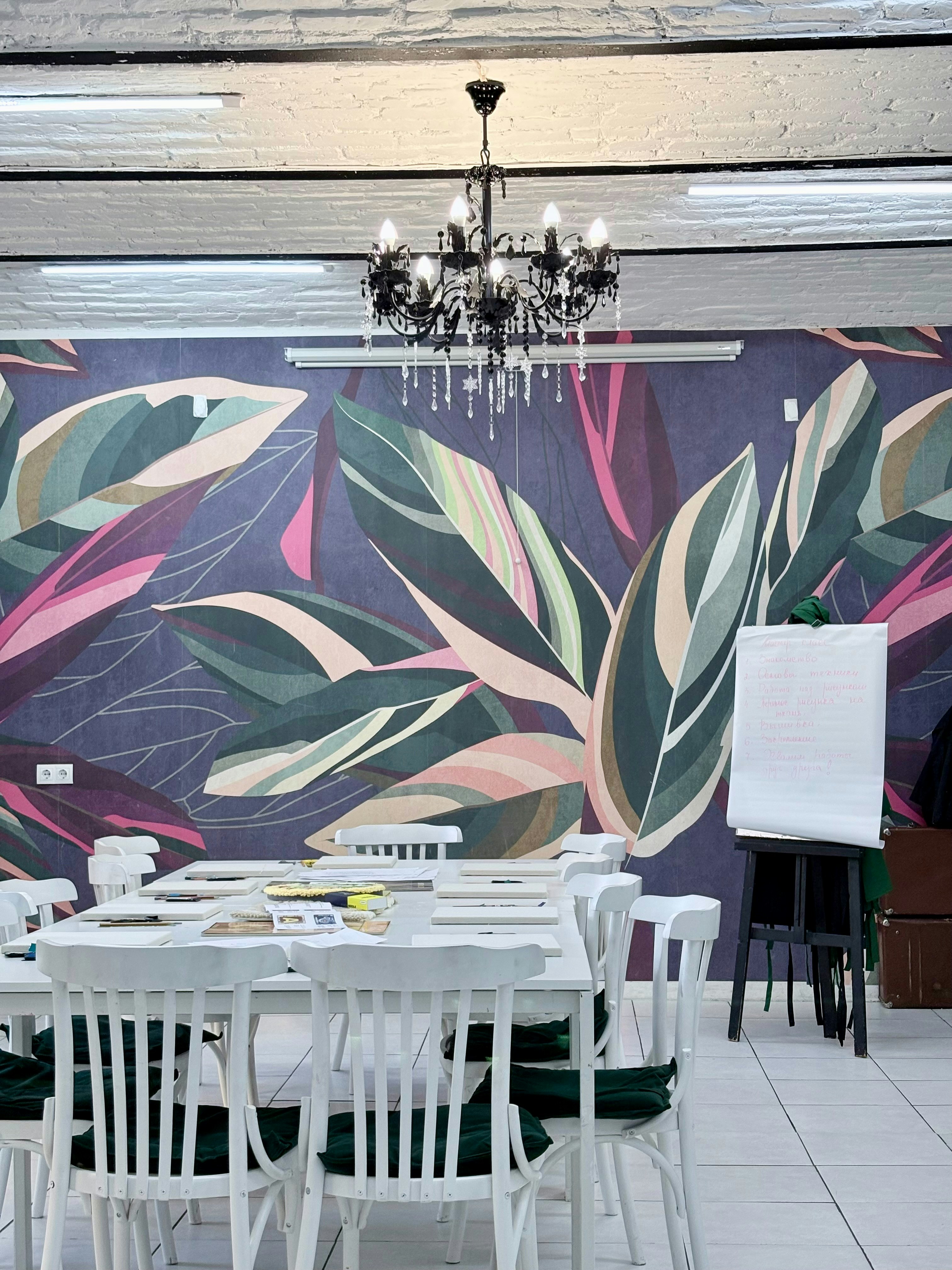 Ruang pertemuan modern dengan wallpaper bunga dan meja putih.