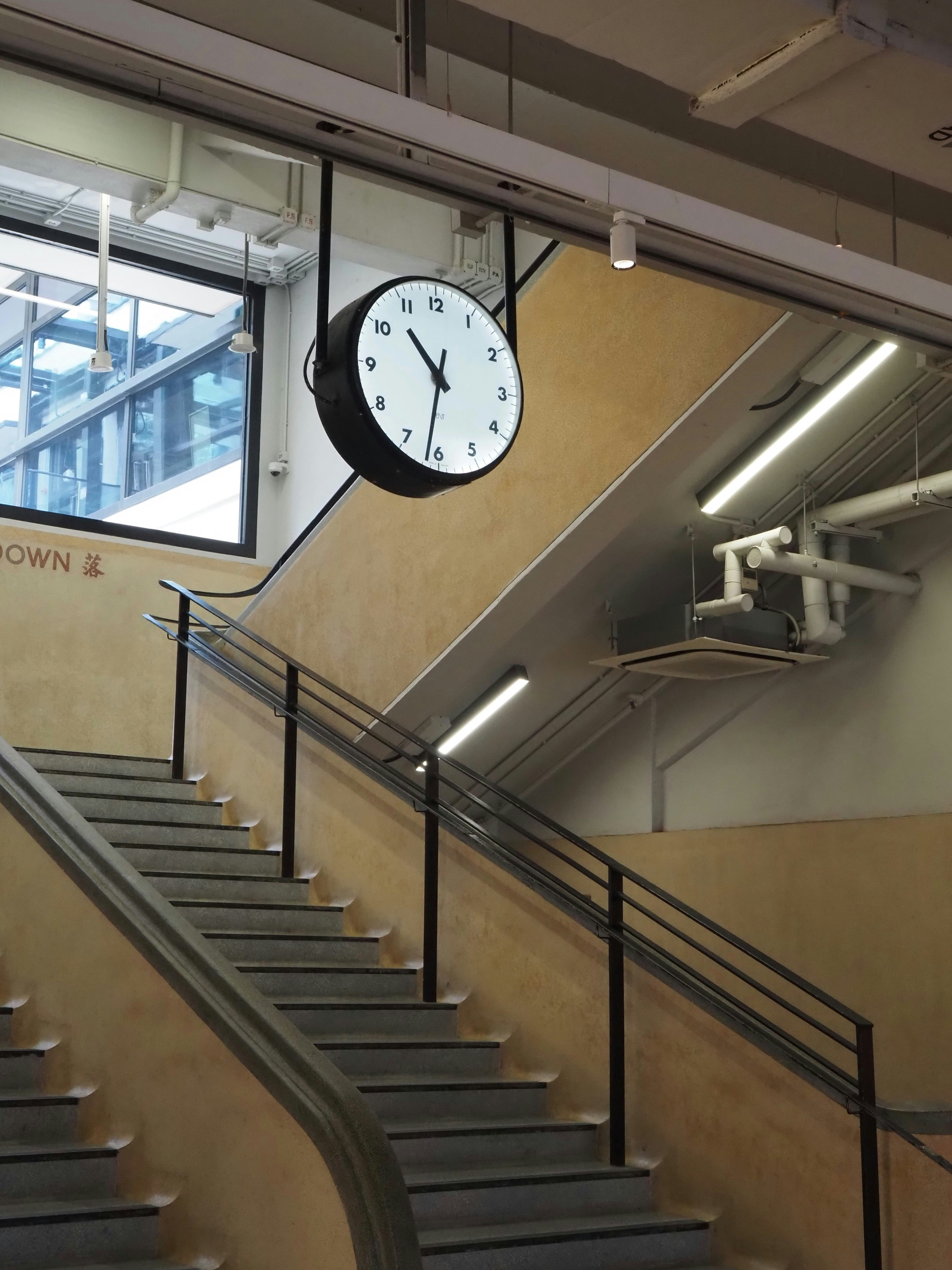 Un gran reloj redondo cuelga sobre una escalera.