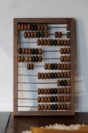 Vintage wooden abacus with beads on metal rods.