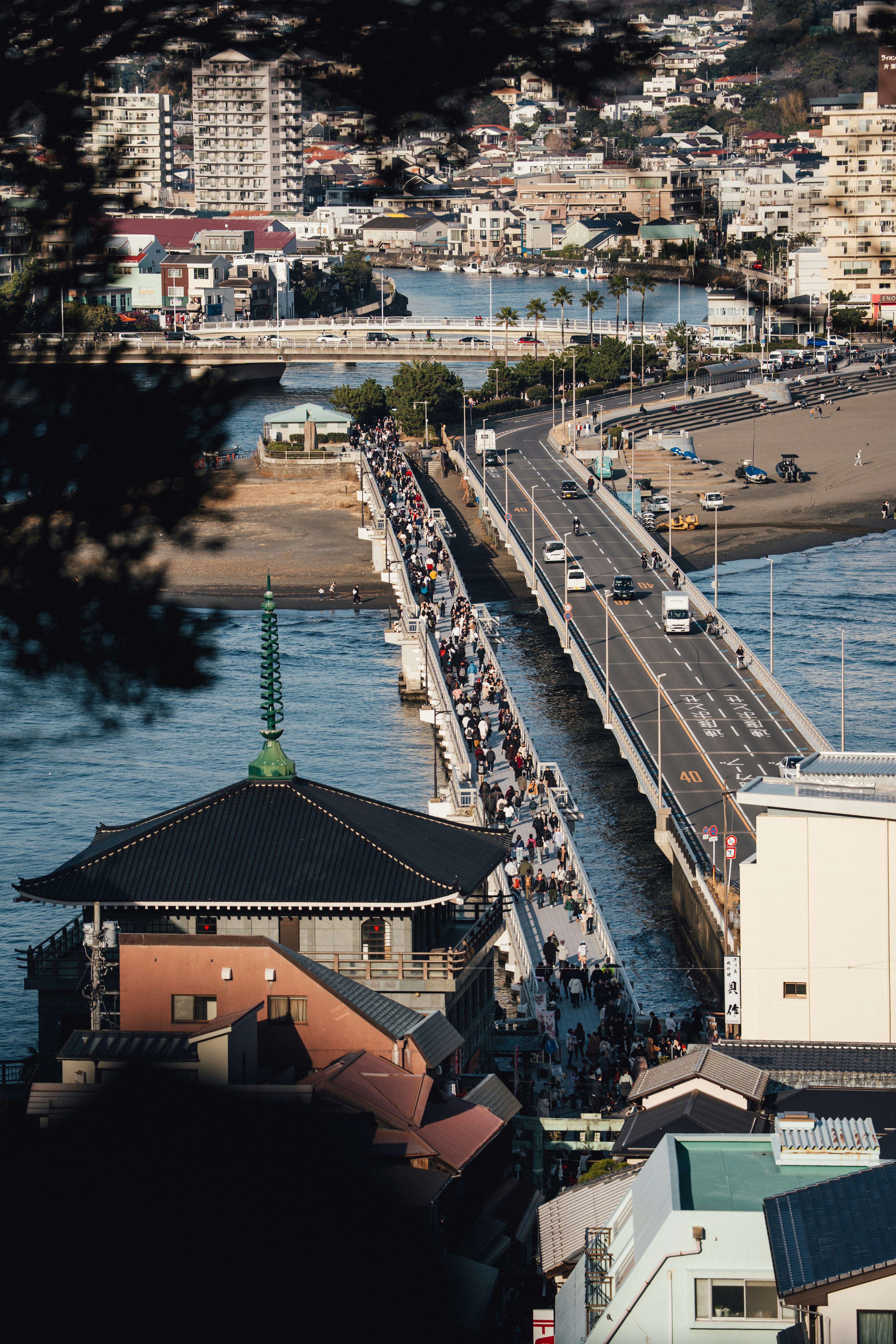 A bustling bridge with many people crossing over water.