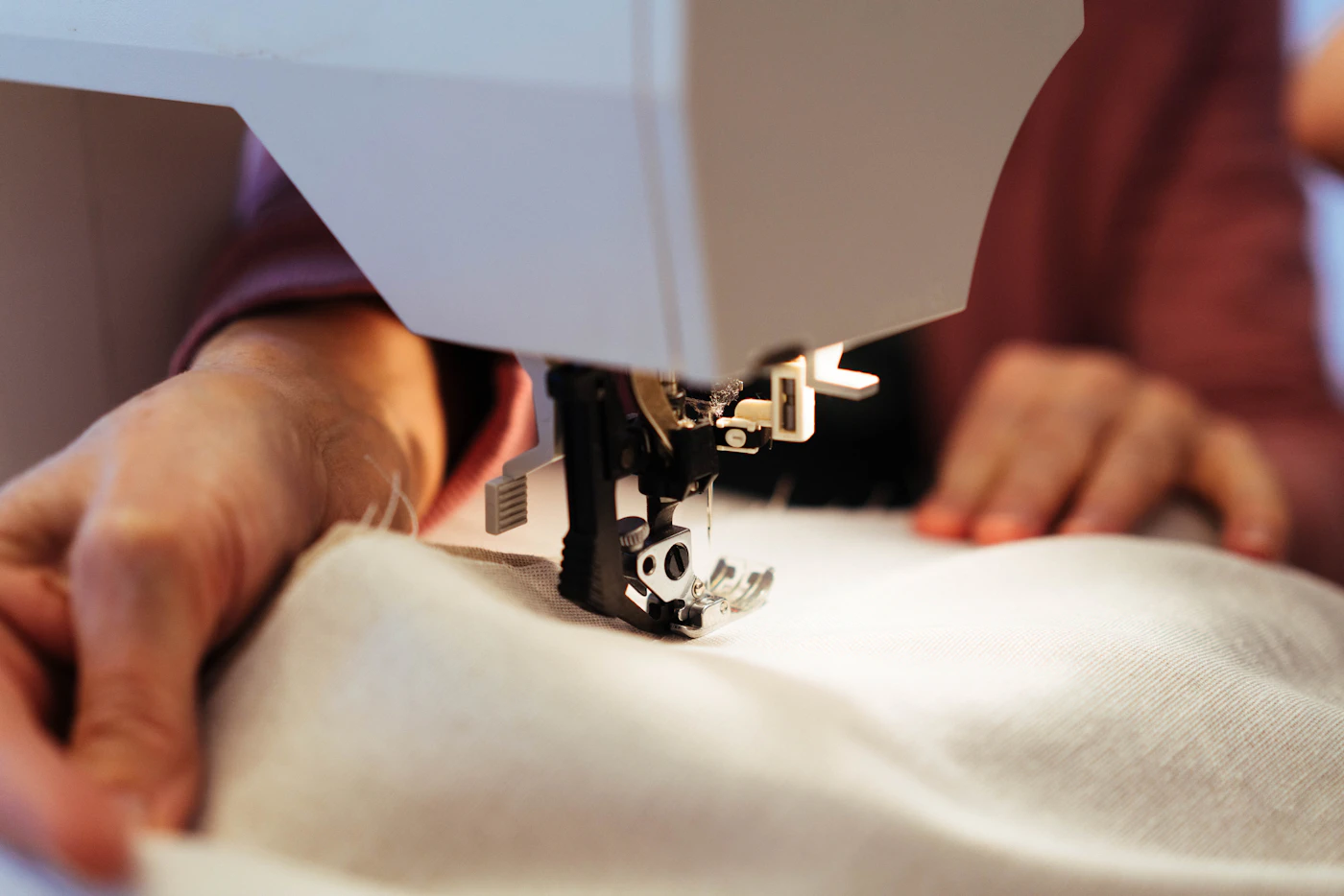 Hands guiding cloth through a sewing machine at the Aisling & Co. workbench