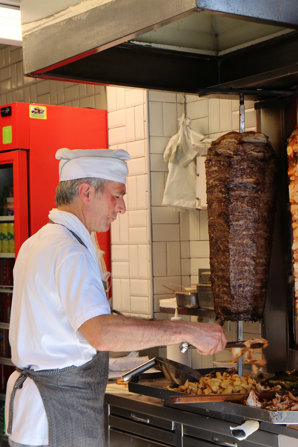 Immagine dimostrativa di un cuoco che affetta carne di döner kebap