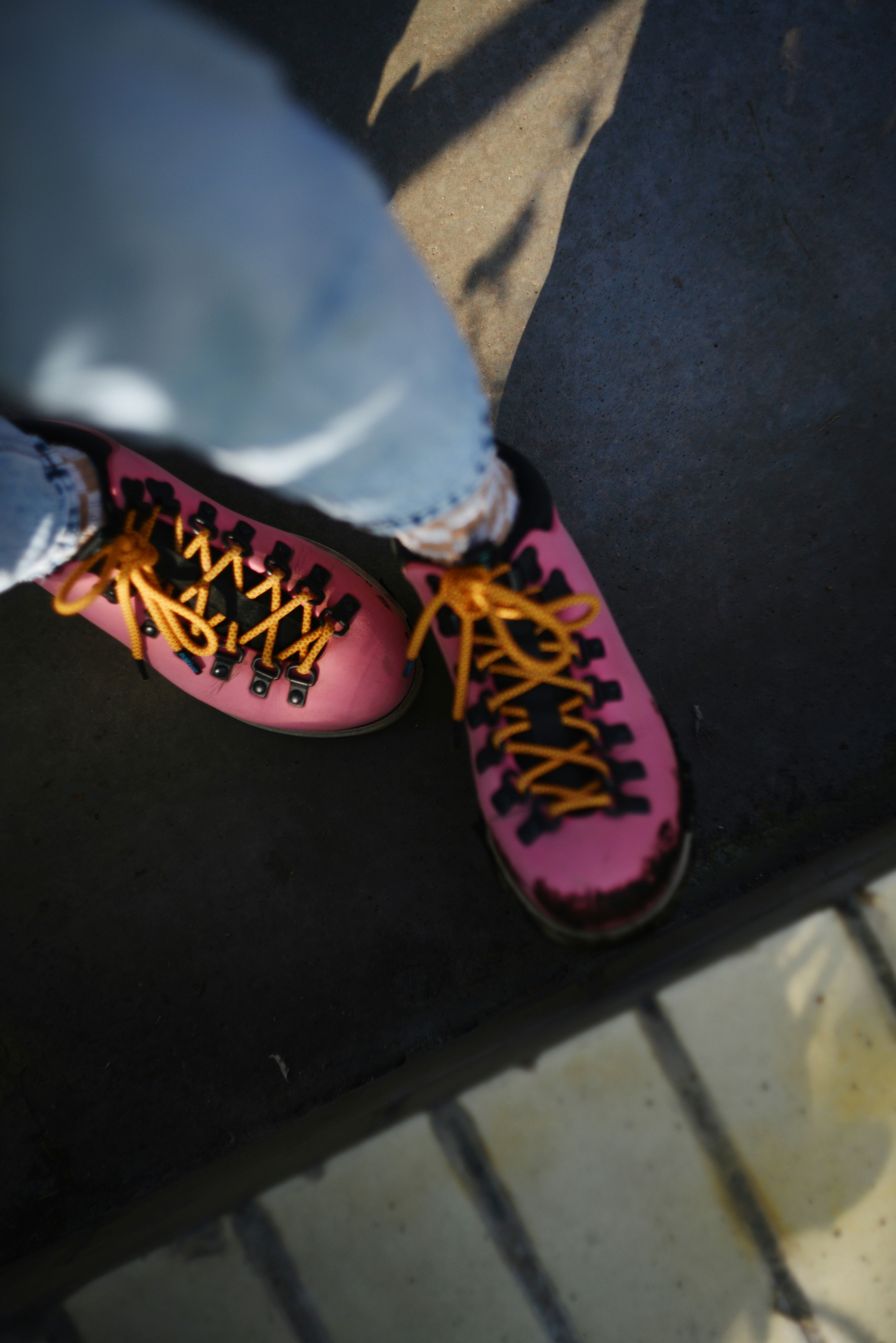 Pink shoes with yellow laces on person's feet