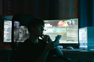 Person looking at phone in front of multiple computer monitors