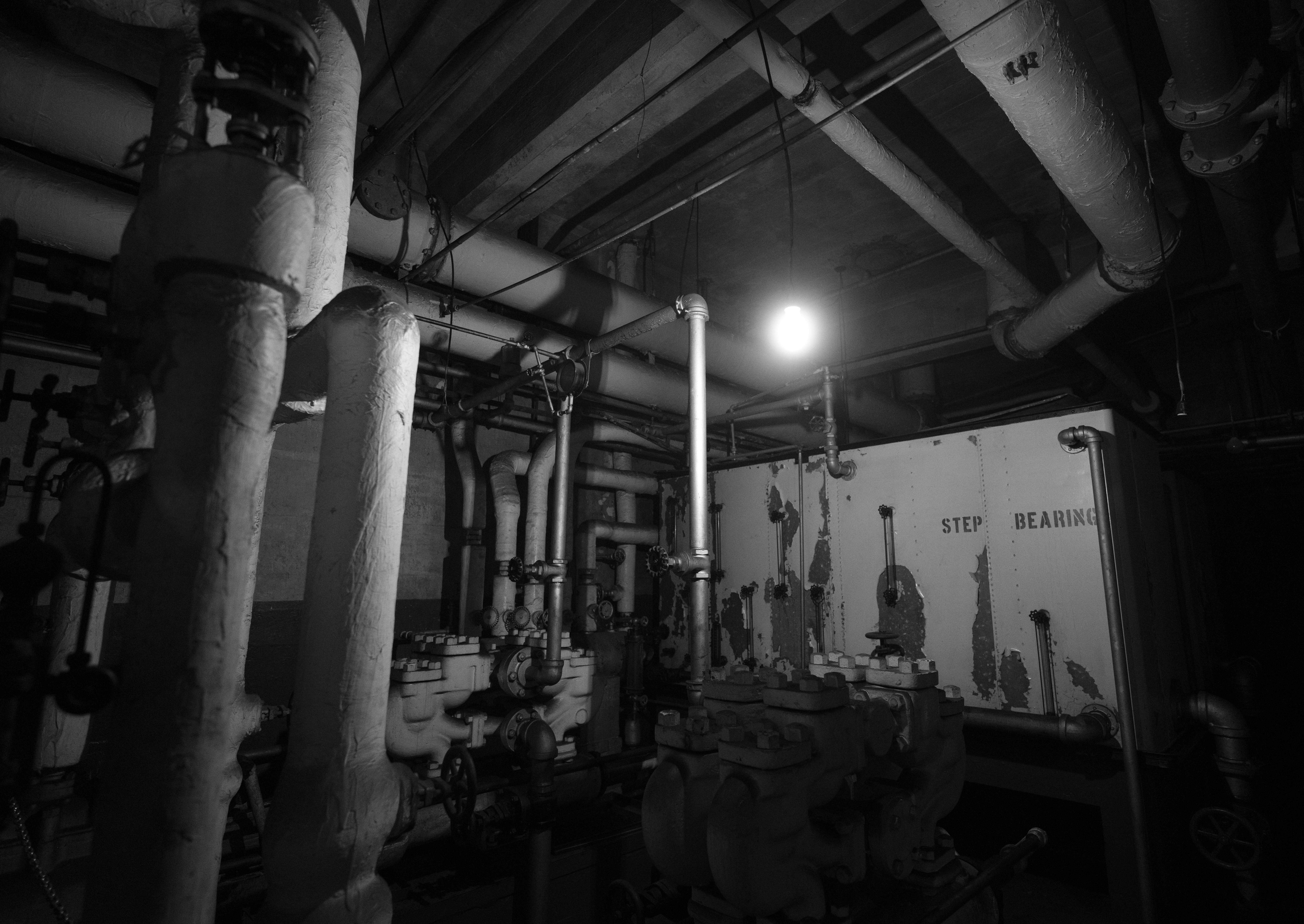 Industrial pipes and machinery in dimly lit basement