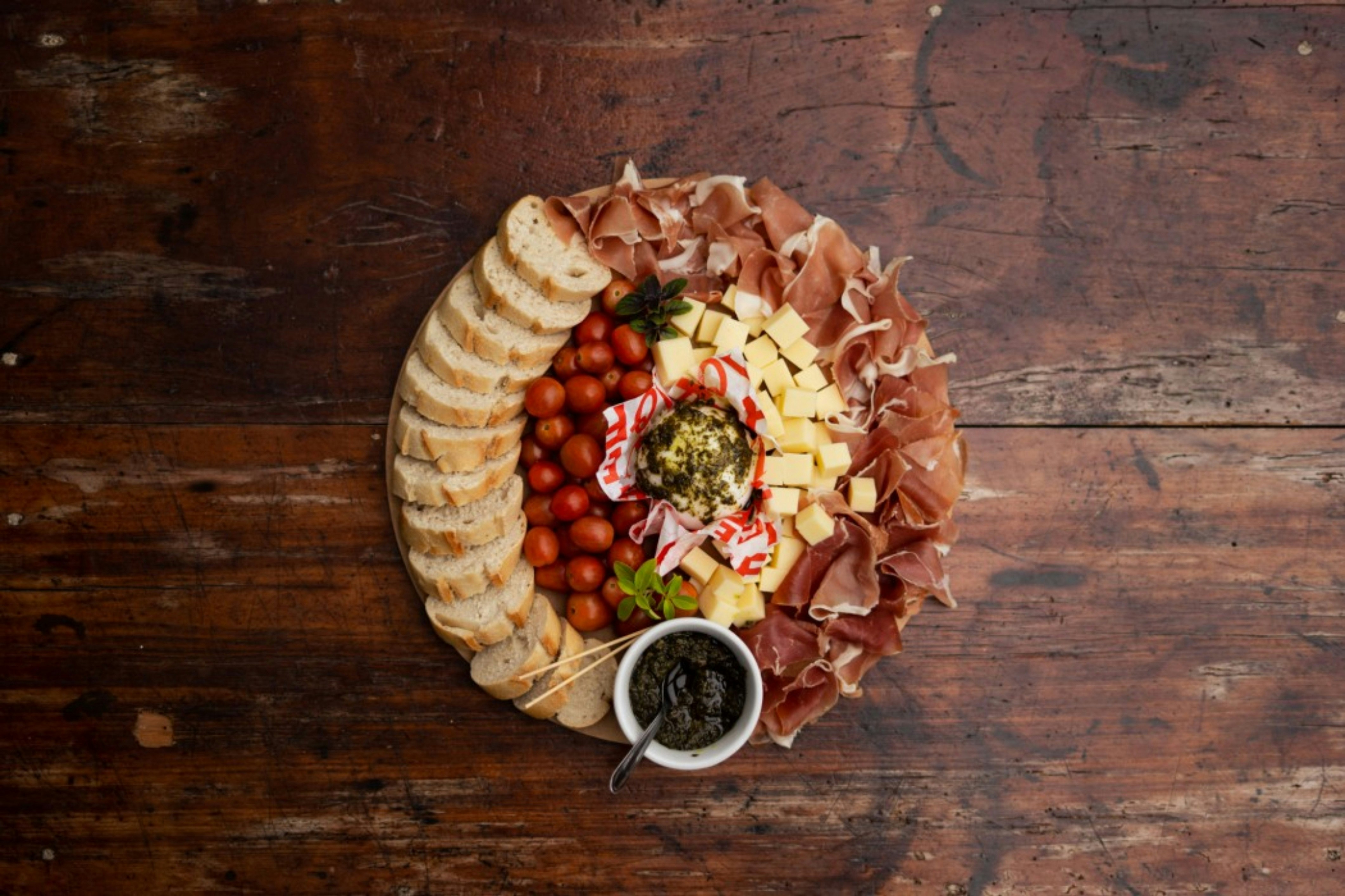 Charcuterie board with bread, cheese, tomatoes, and olives