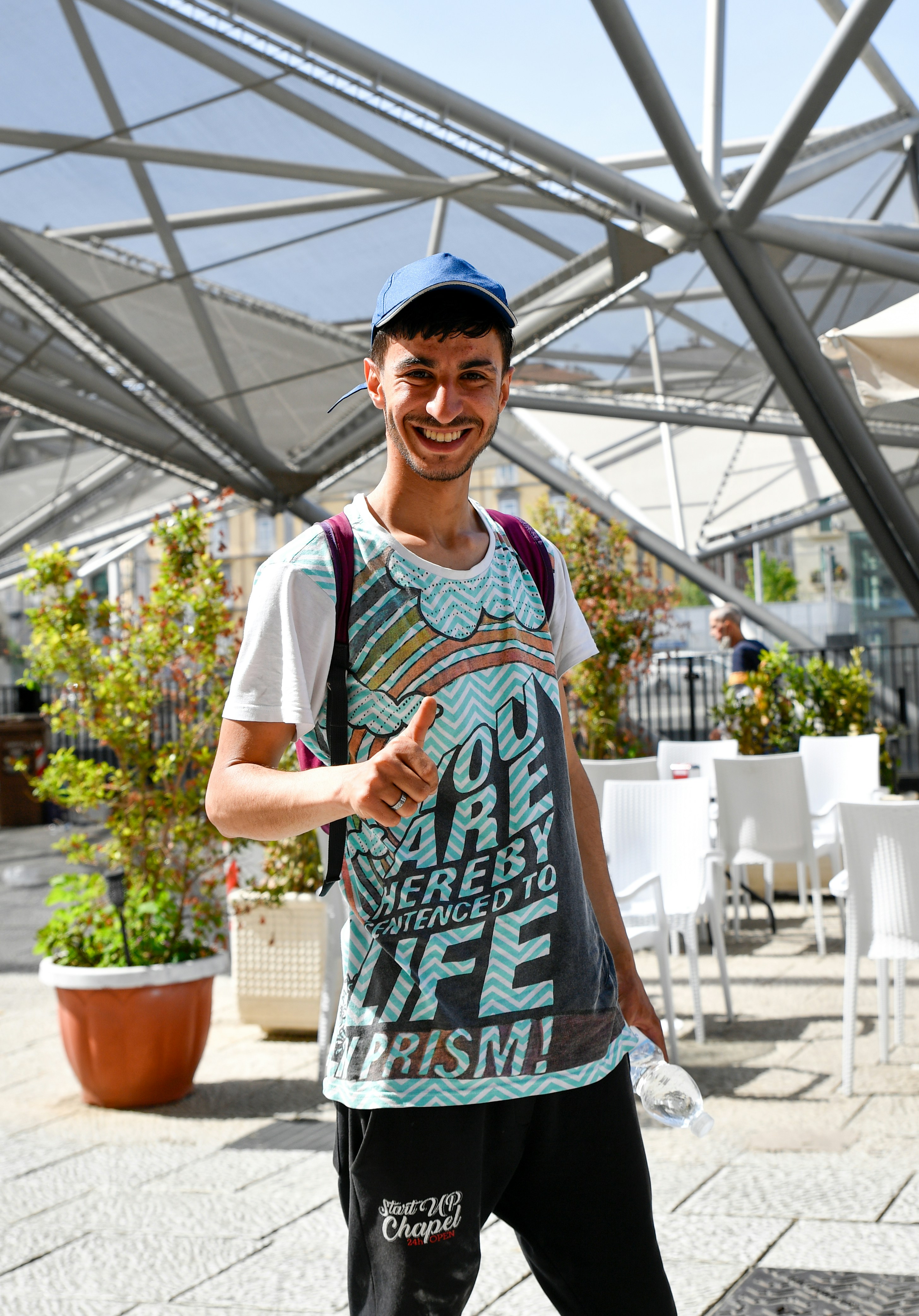 Man in a colorful t-shirt gives a thumbs up.