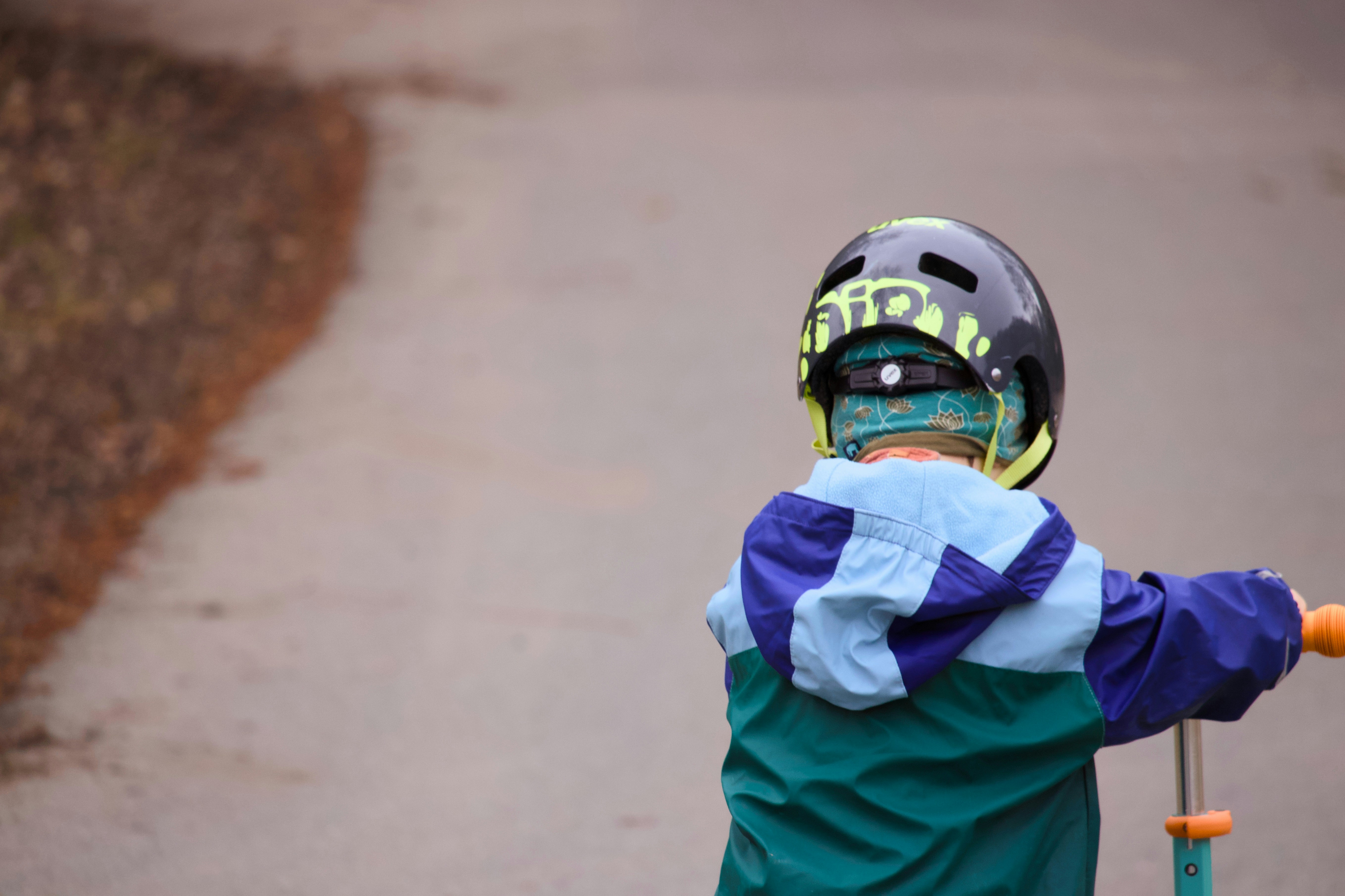Child in helmet riding a scooter outdoors