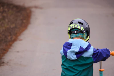 Child in helmet riding a scooter outdoors