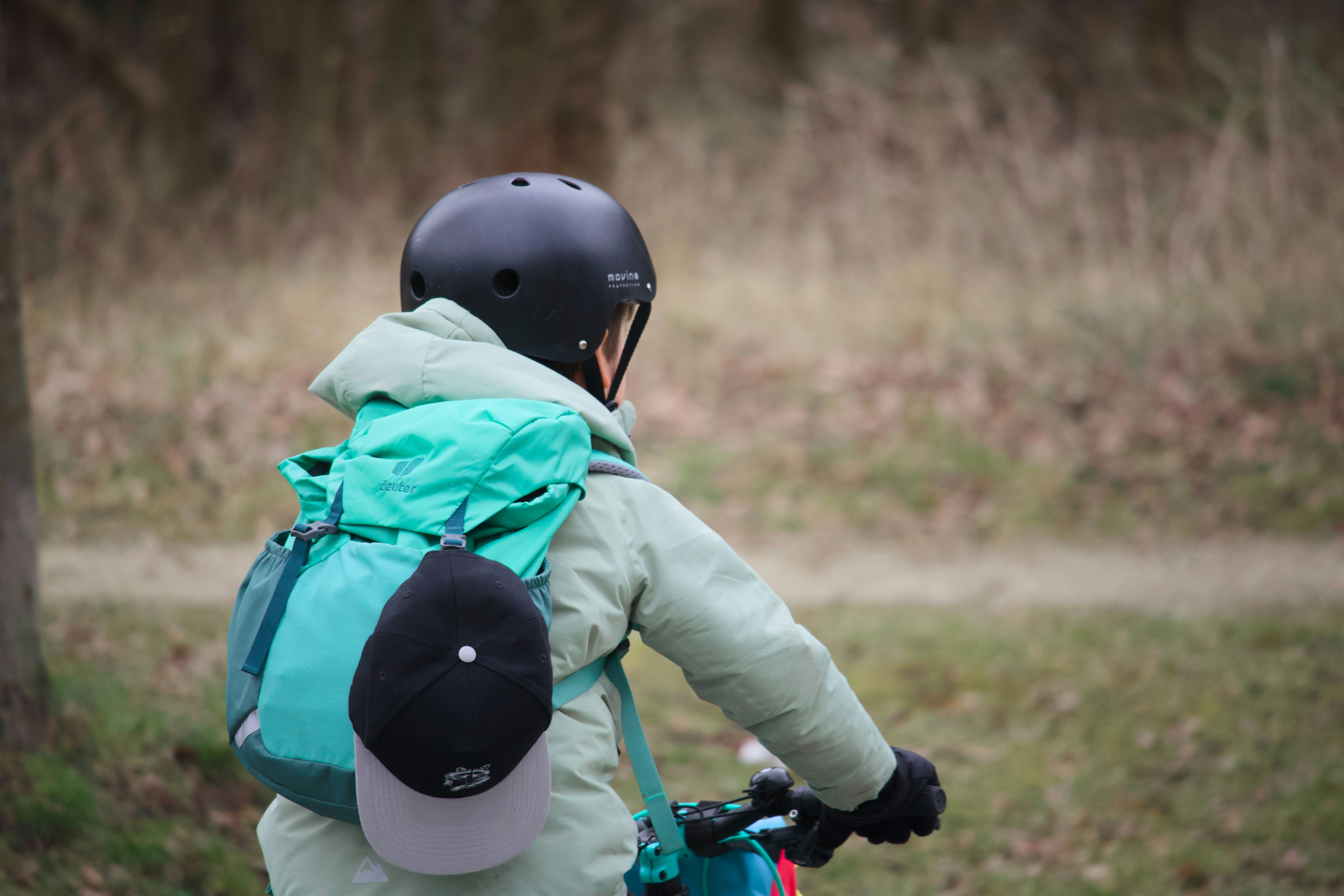 Child wearing helmet and backpack riding a bicycle