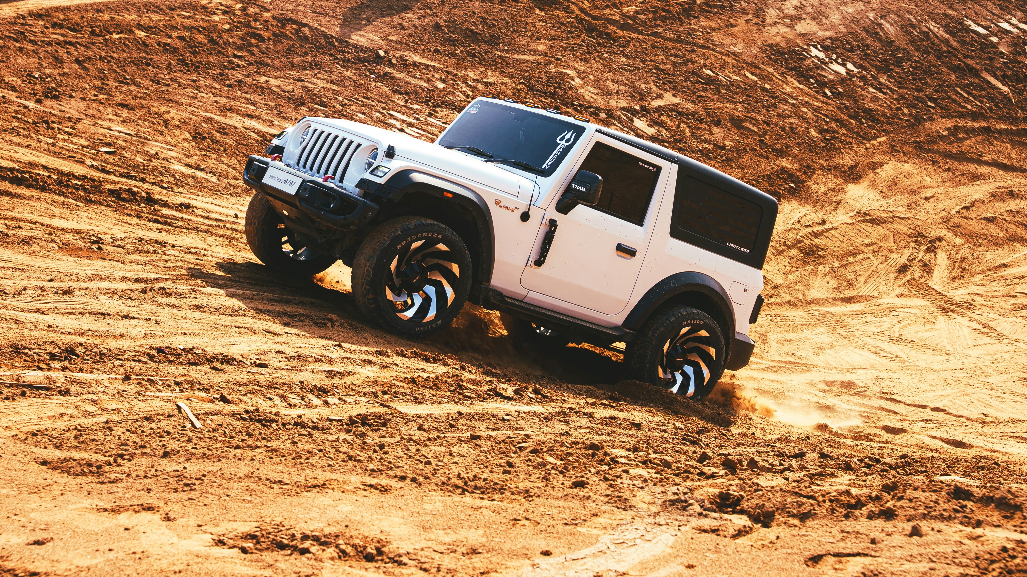 Véhicule tout-terrain blanc montant une colline de terre.