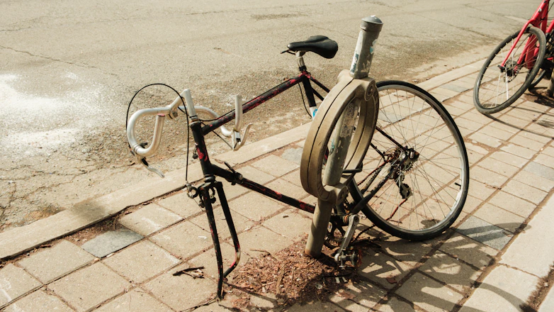 A bicycle locked to a pole on a sidewalk.