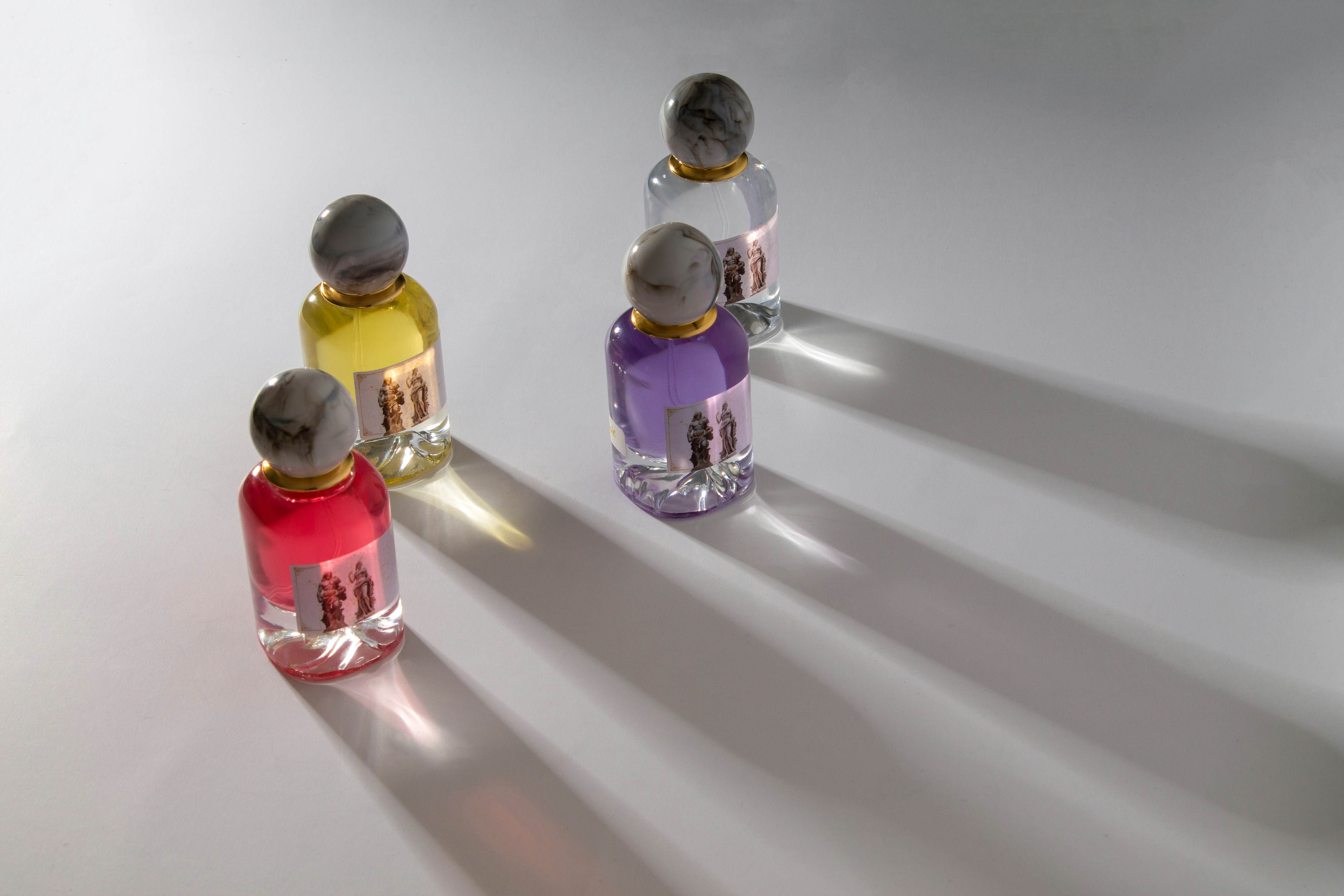 Four colorful perfume bottles casting long shadows