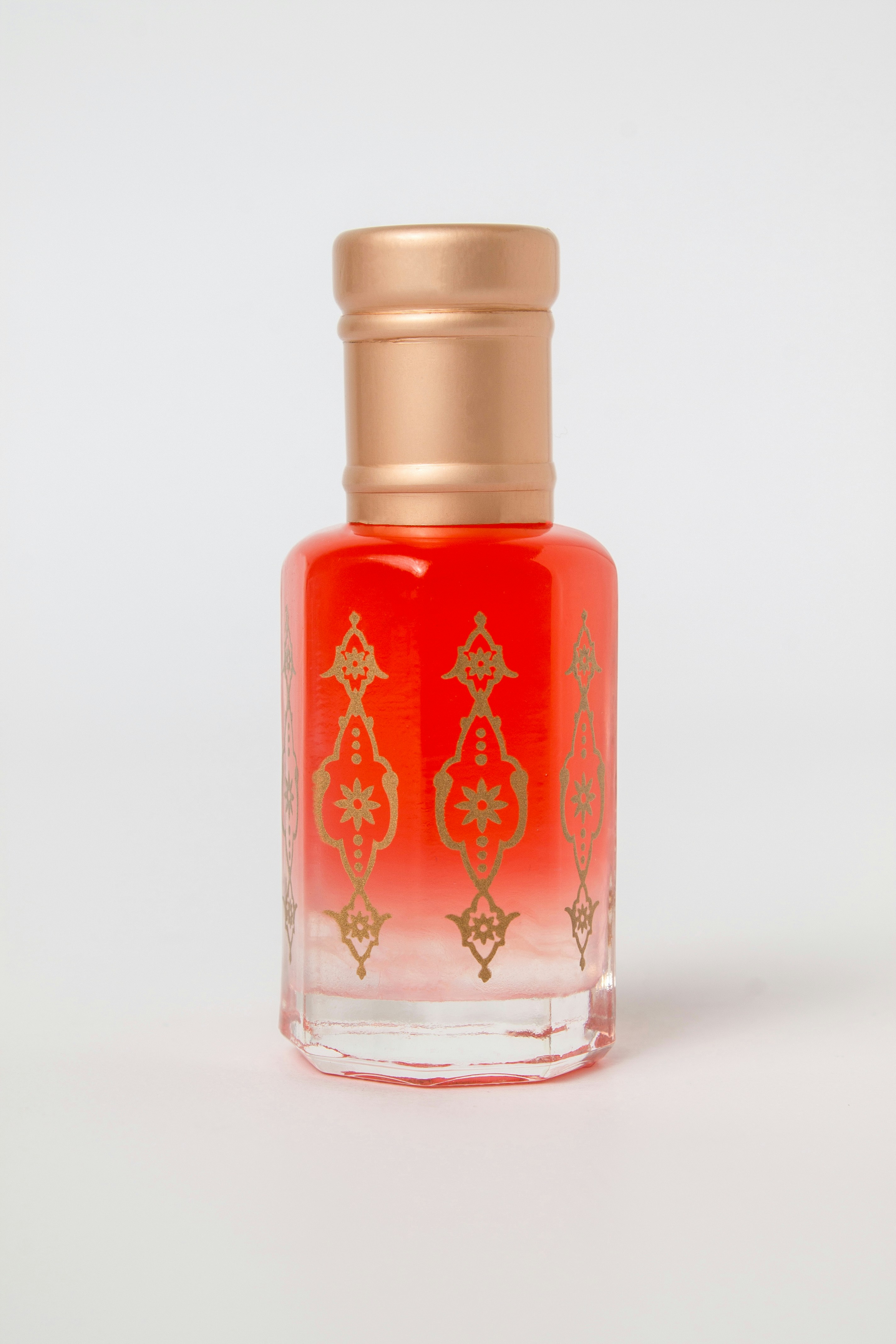 Une petite bouteille en verre avec des motifs de liquide rouge et d’or.