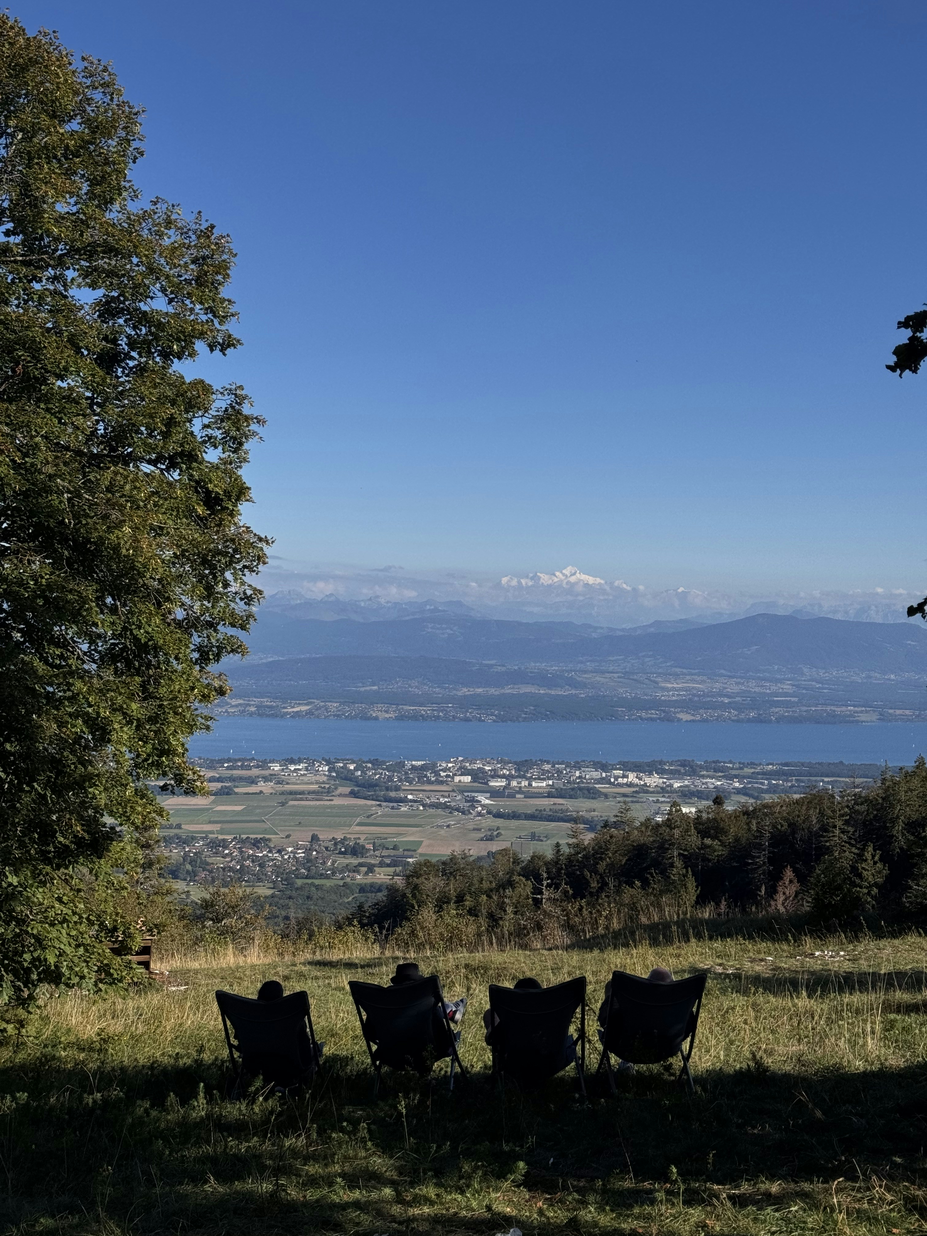Four chairs facing a scenic lake and distant mountains.
