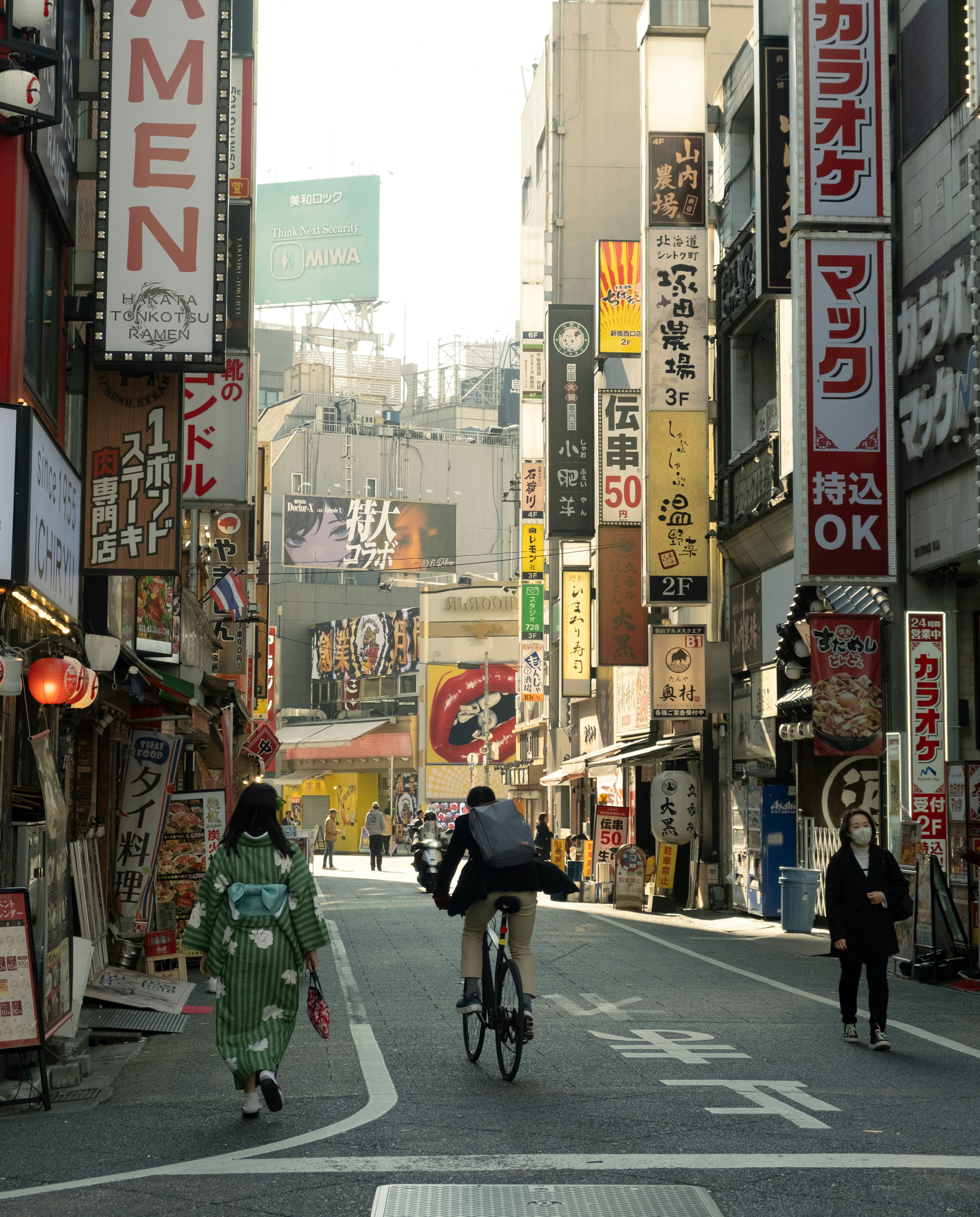People walk down a street lined with japanese signs