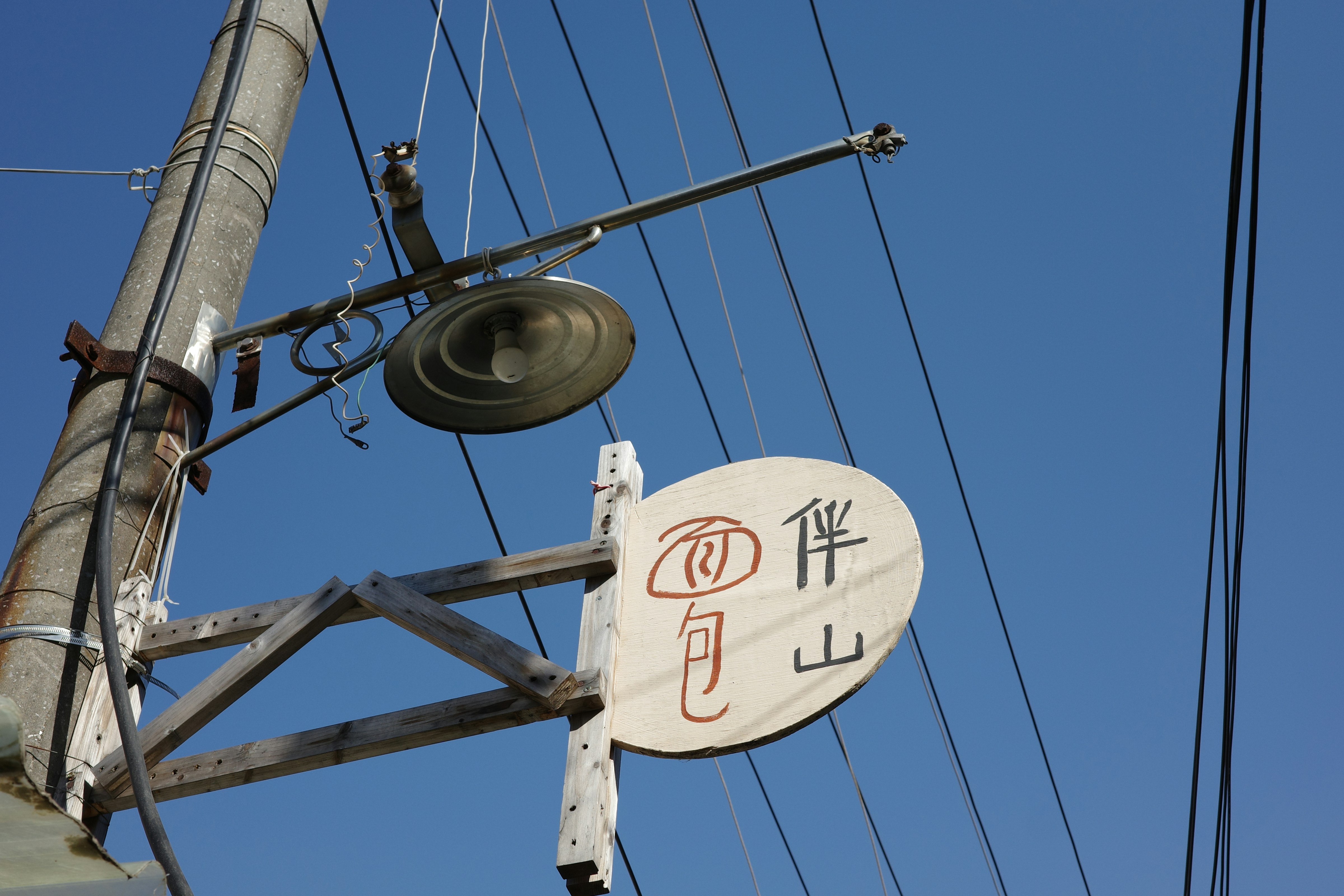 ポールに日本語の文字が書かれた通りの標識。