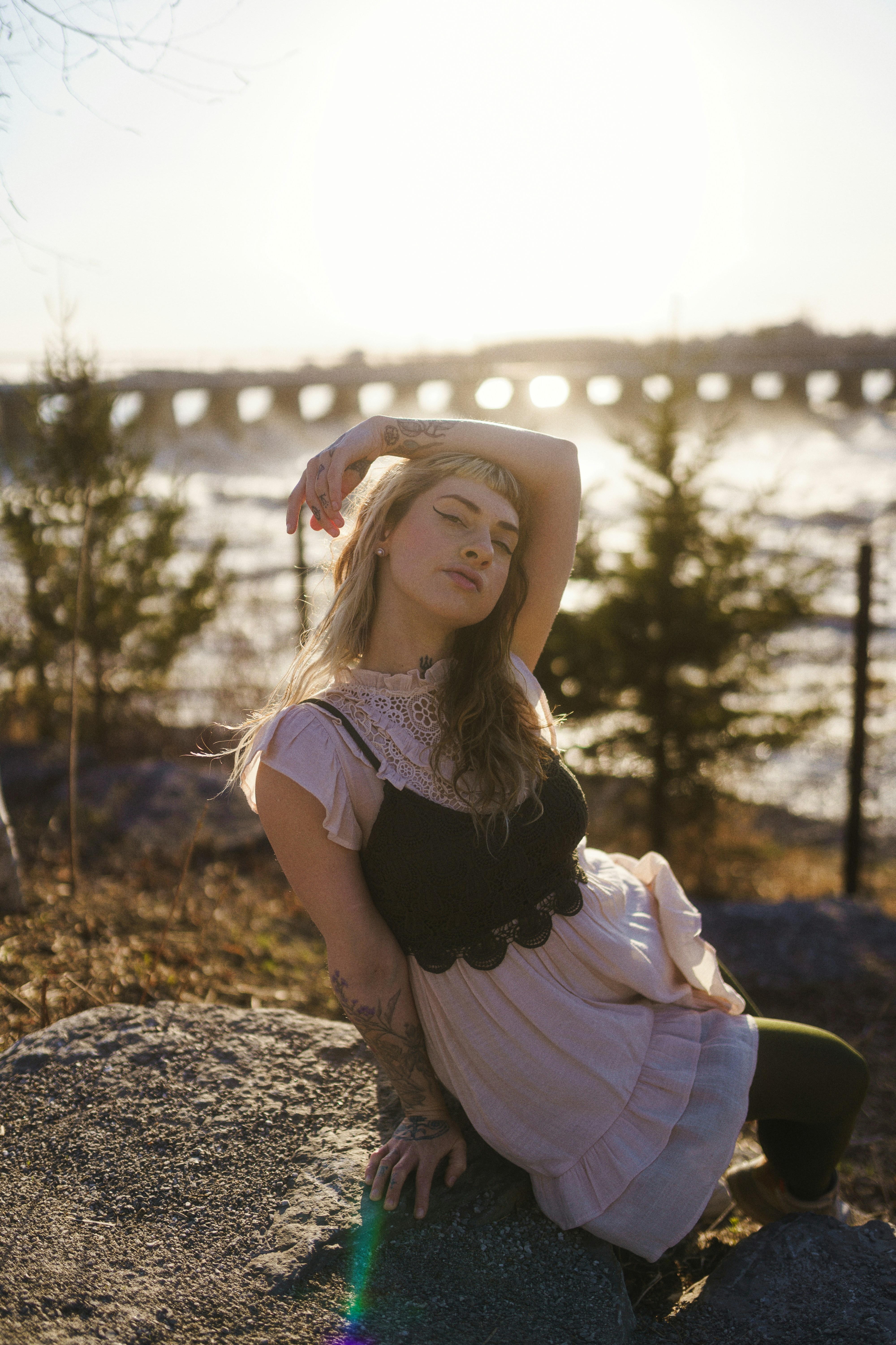 Woman posing outdoors near water with trees