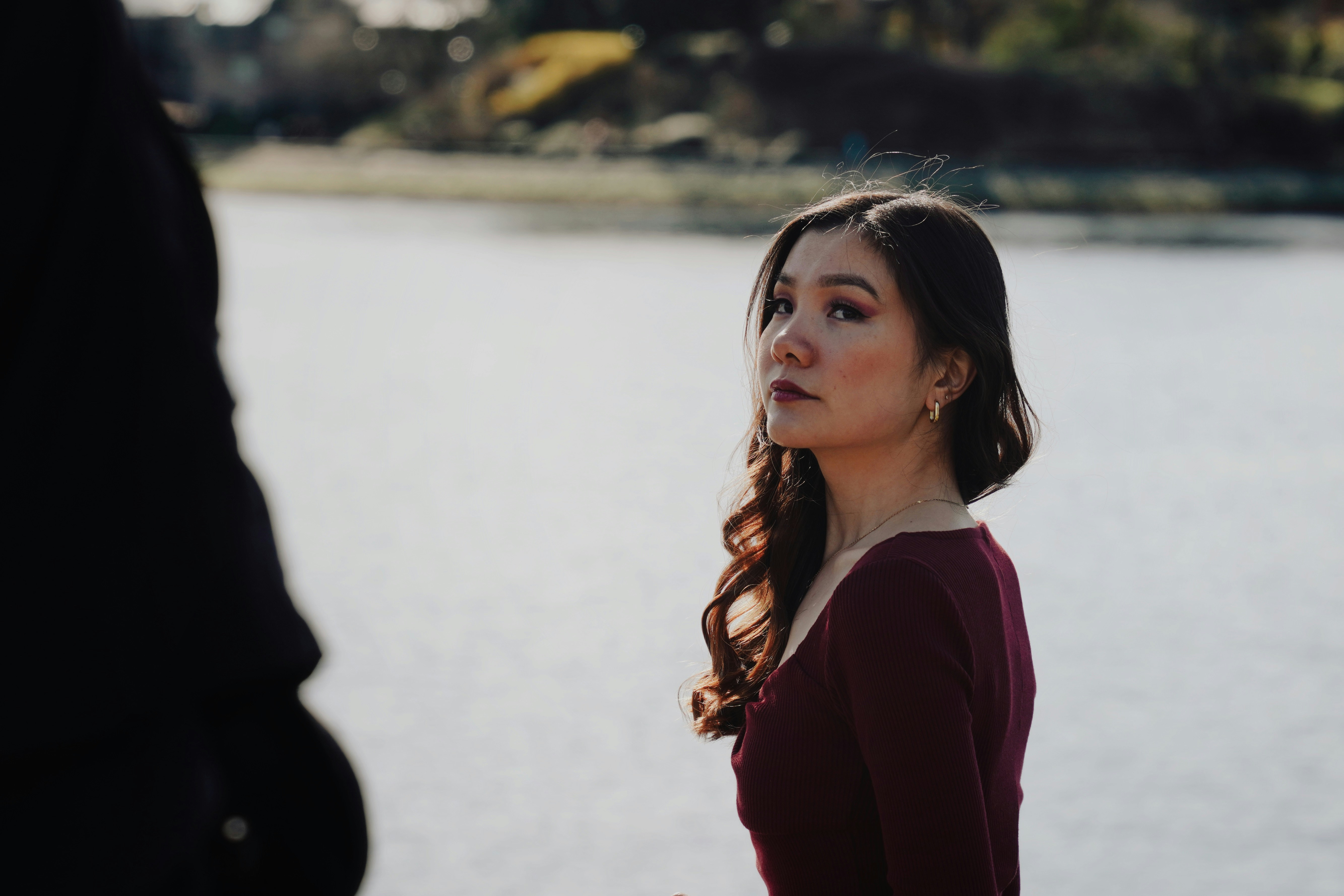 Junge Frau, die über die Schulter am Wasser schaut.