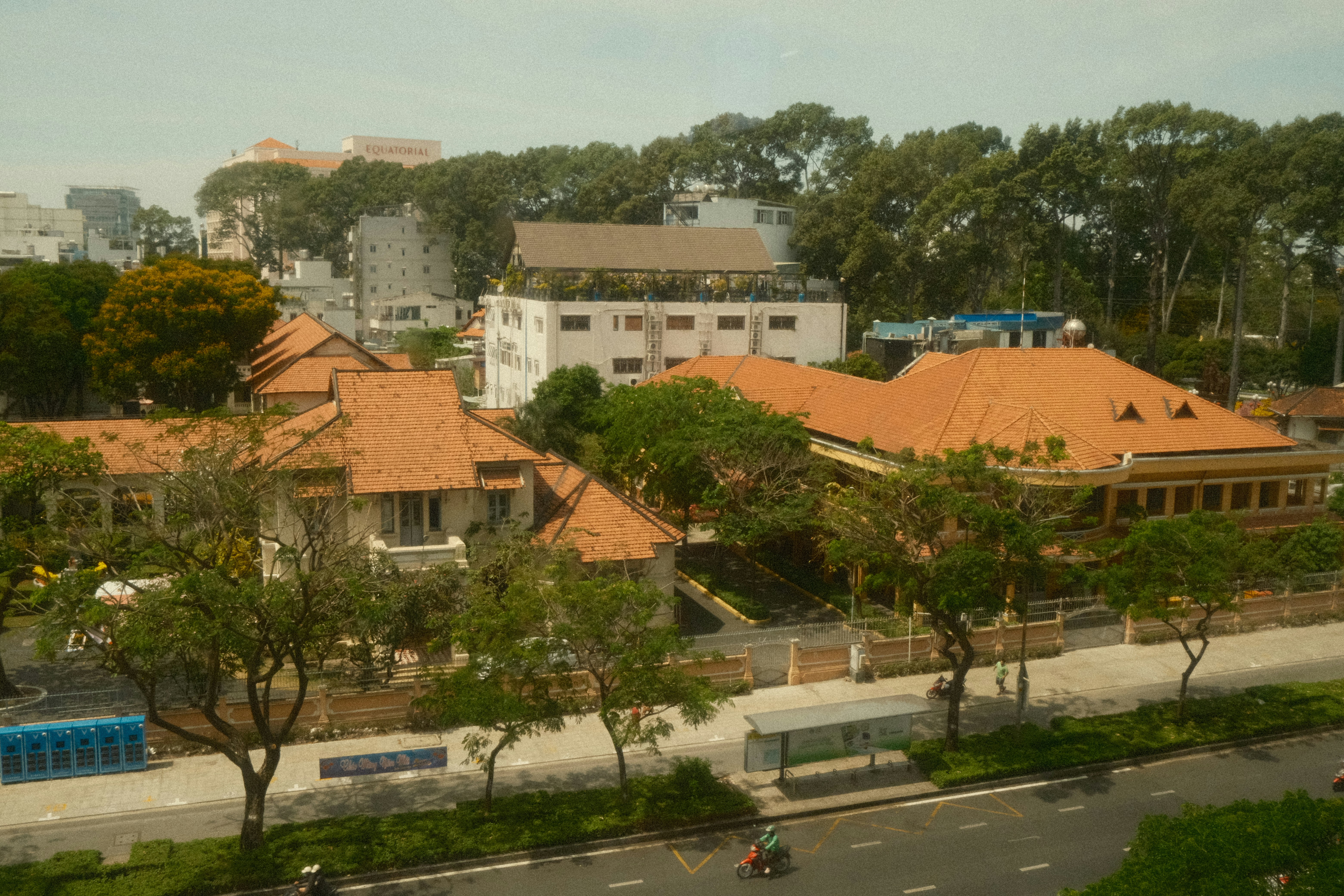 Buildings surrounded by trees with a street in foreground