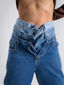 Two pairs of jeans layered on a person.