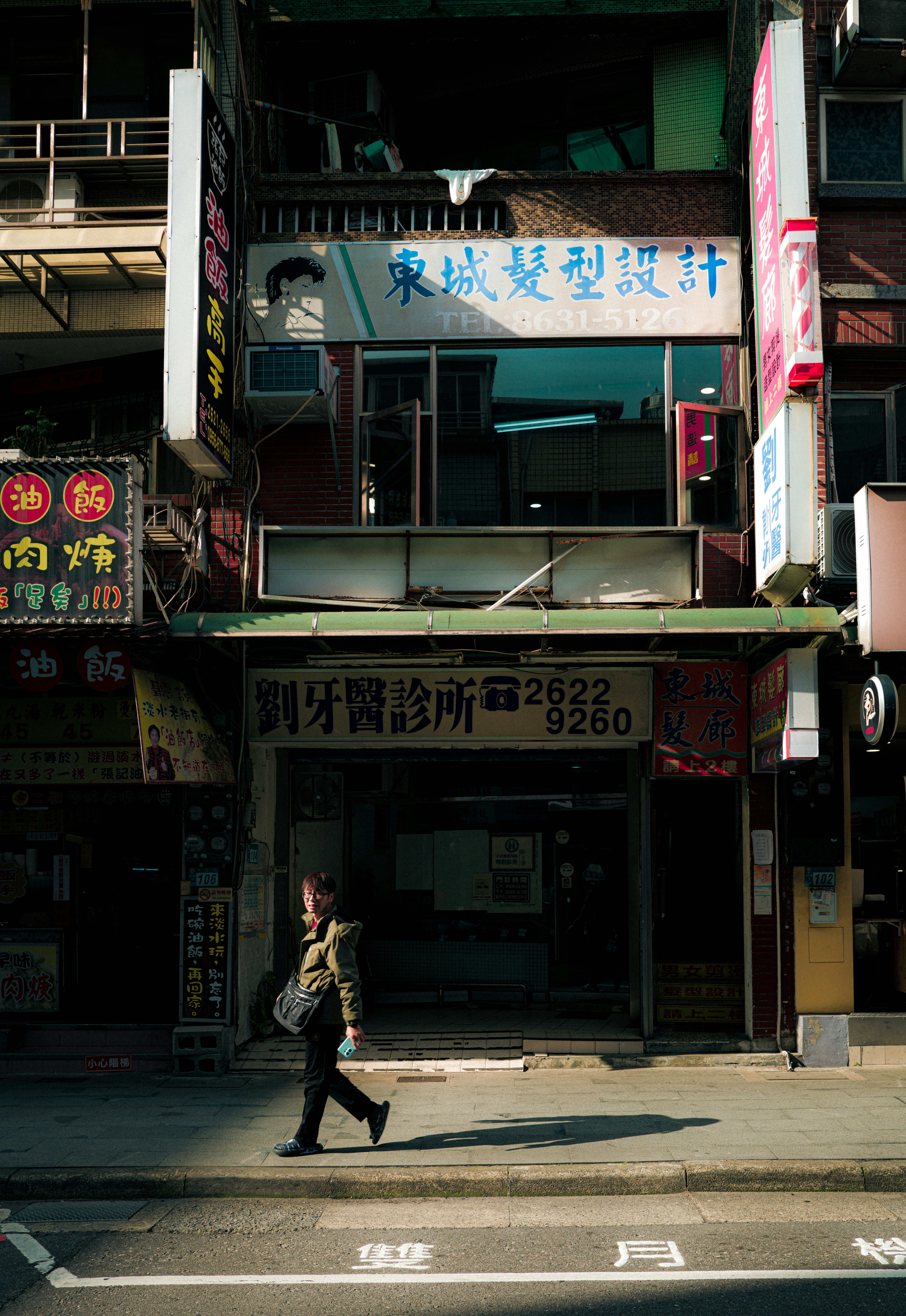 A woman walks past shops on a sunny street. - 相关推荐
