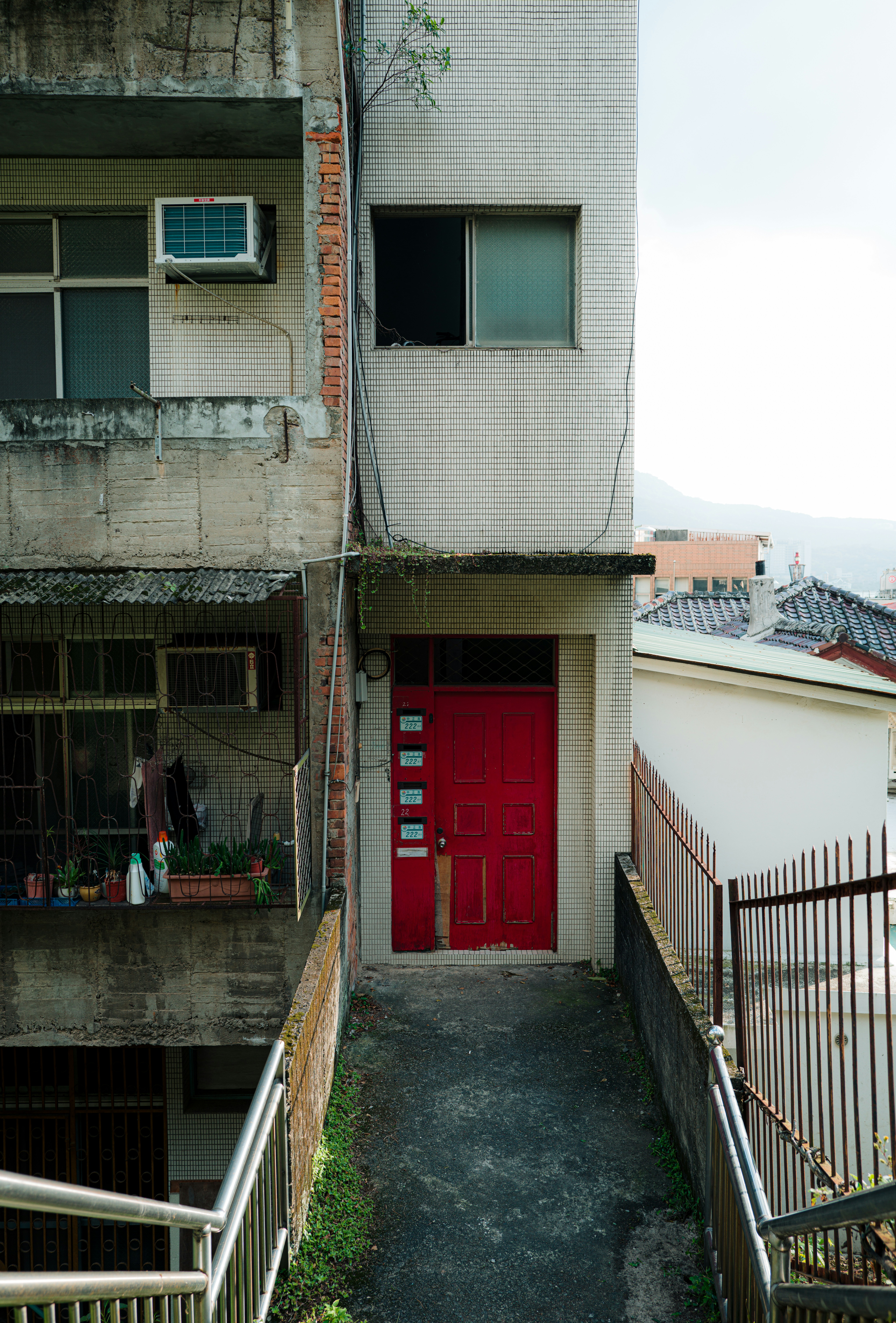 A narrow walkway leads to a bright red door.