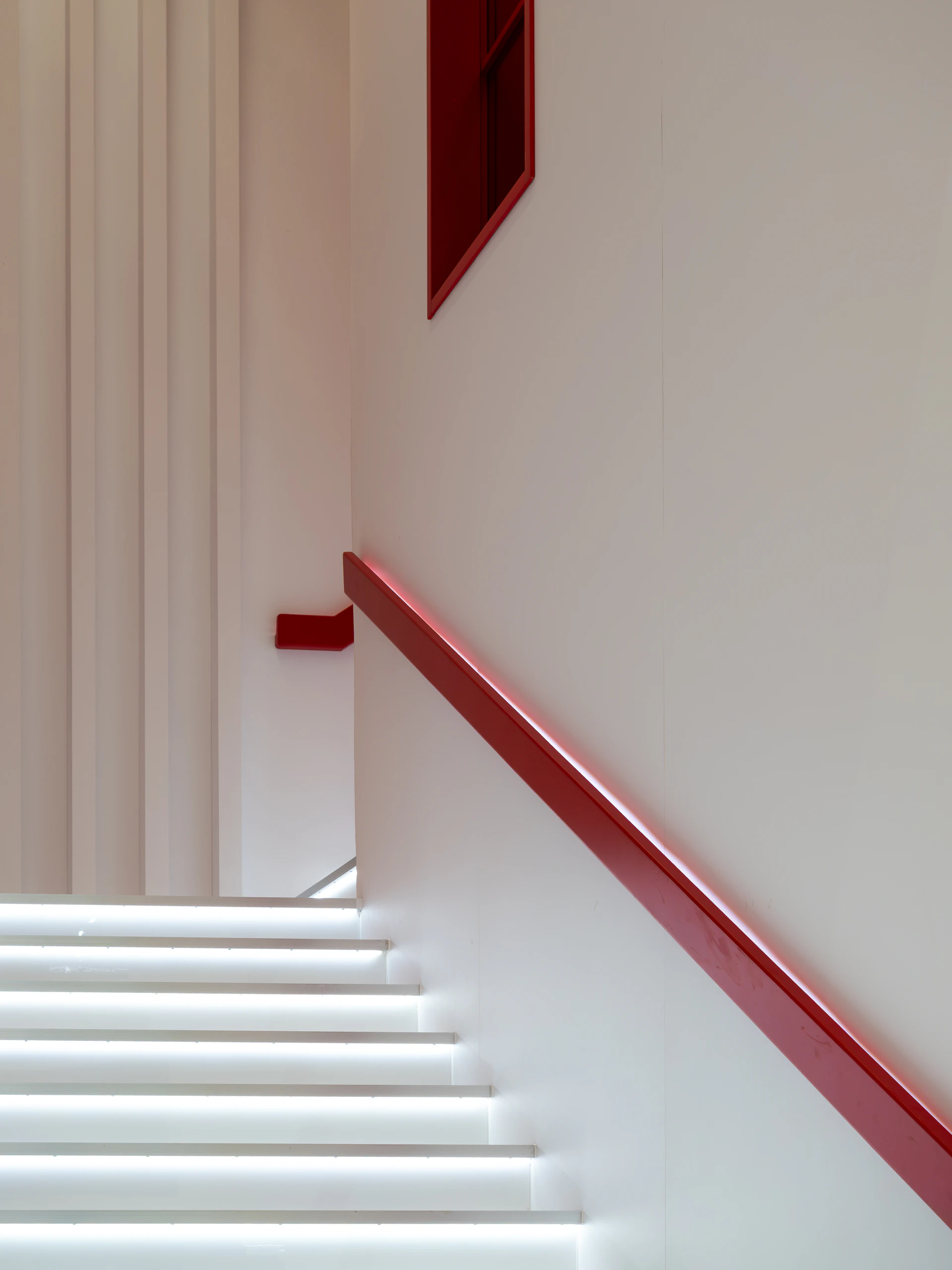 Modern staircase with red railing and illuminated steps