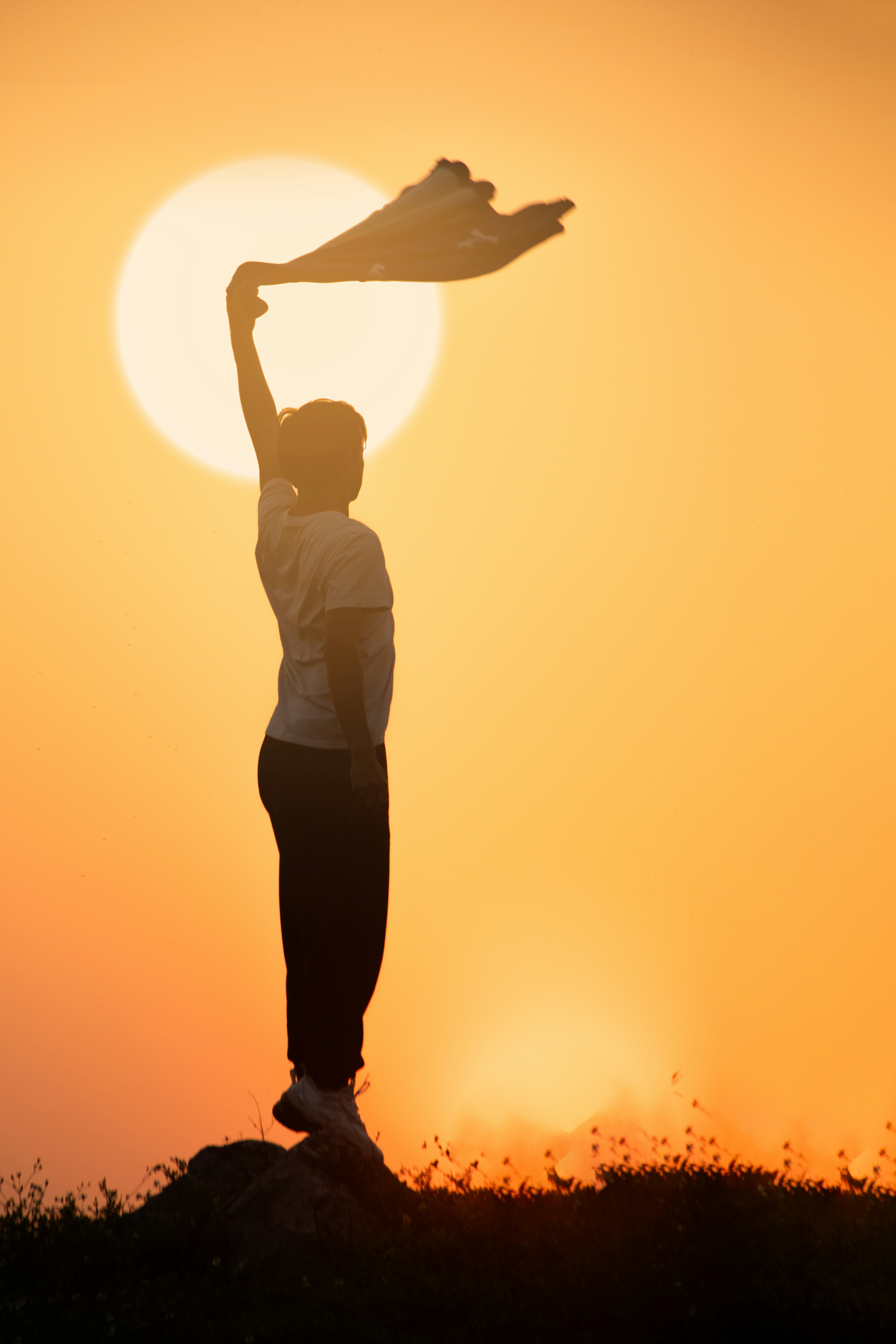 Silhouette of a person holding a scarf against a sunset