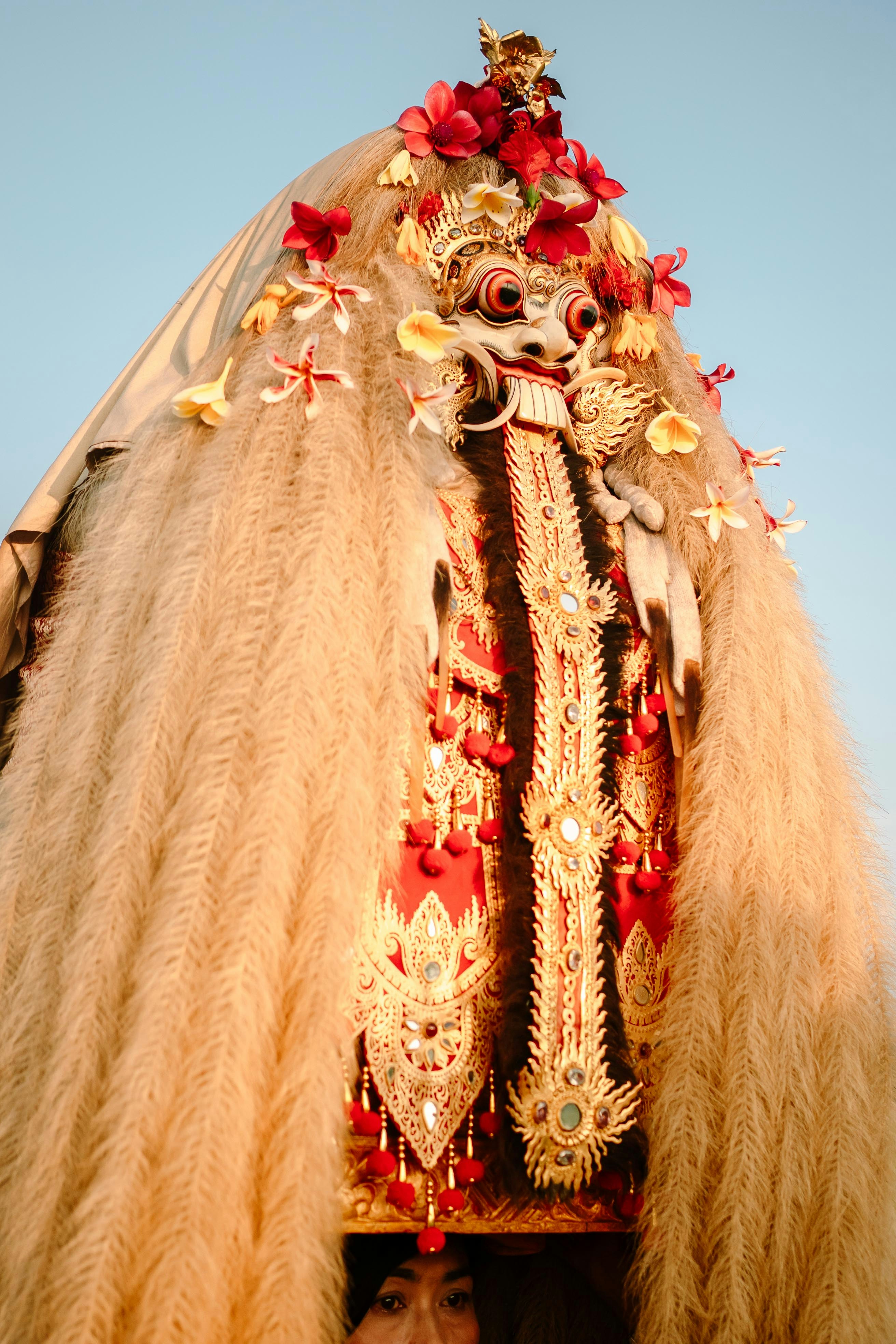 A traditional balinese barong mask costume with flowers.