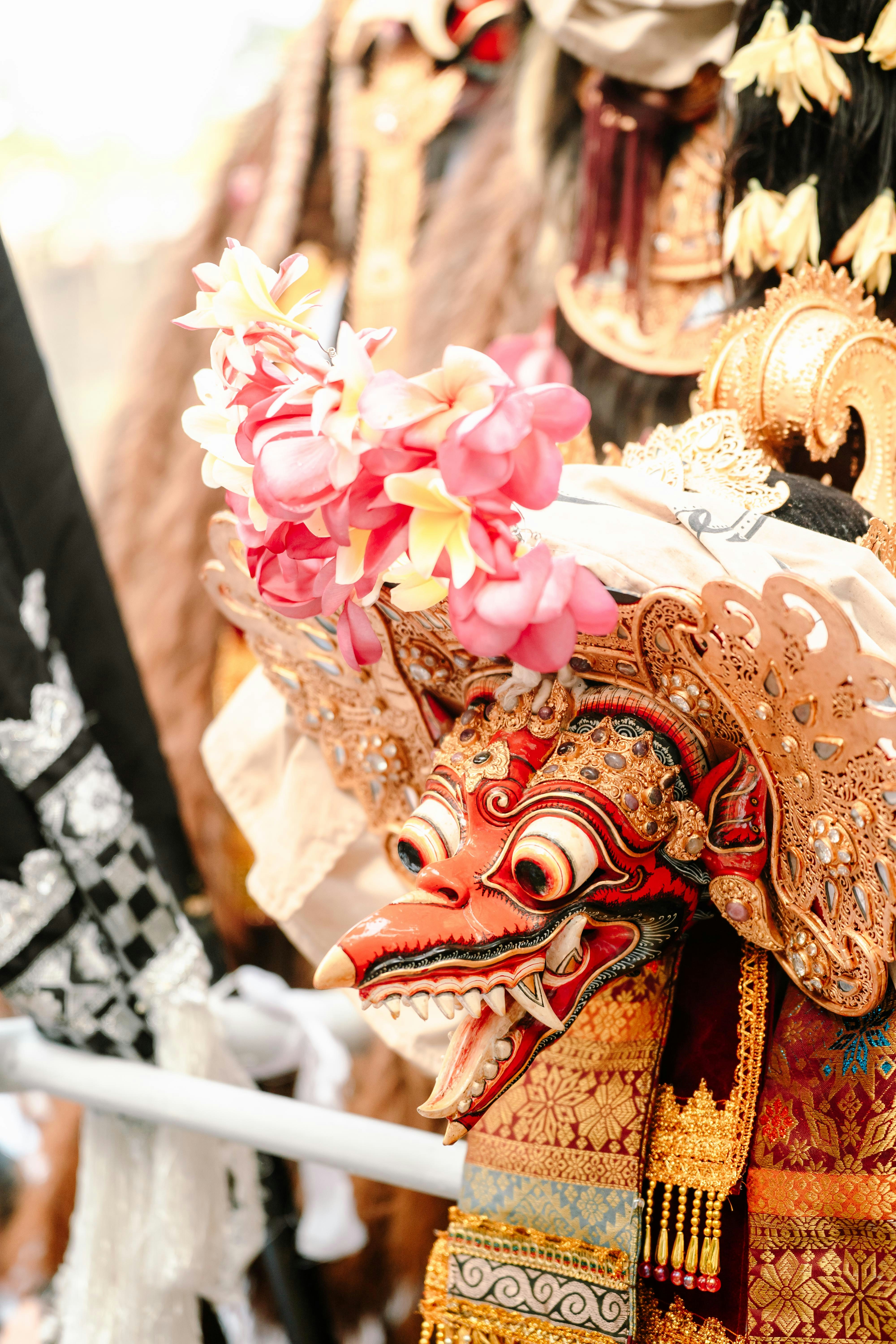 Ornate balinese mask adorned with pink flowers
