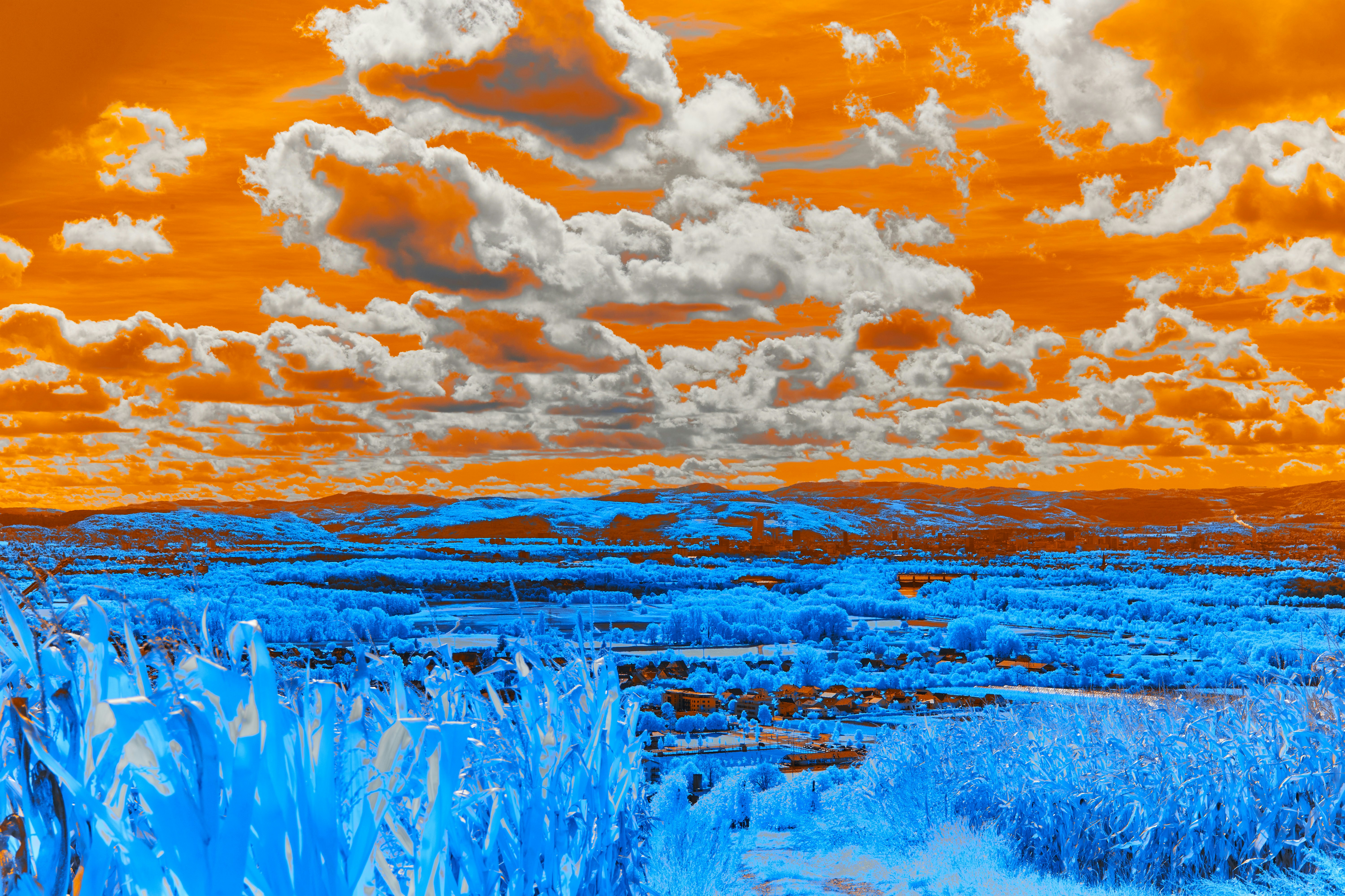 Cielo arancione con nuvole bianche su paesaggio blu