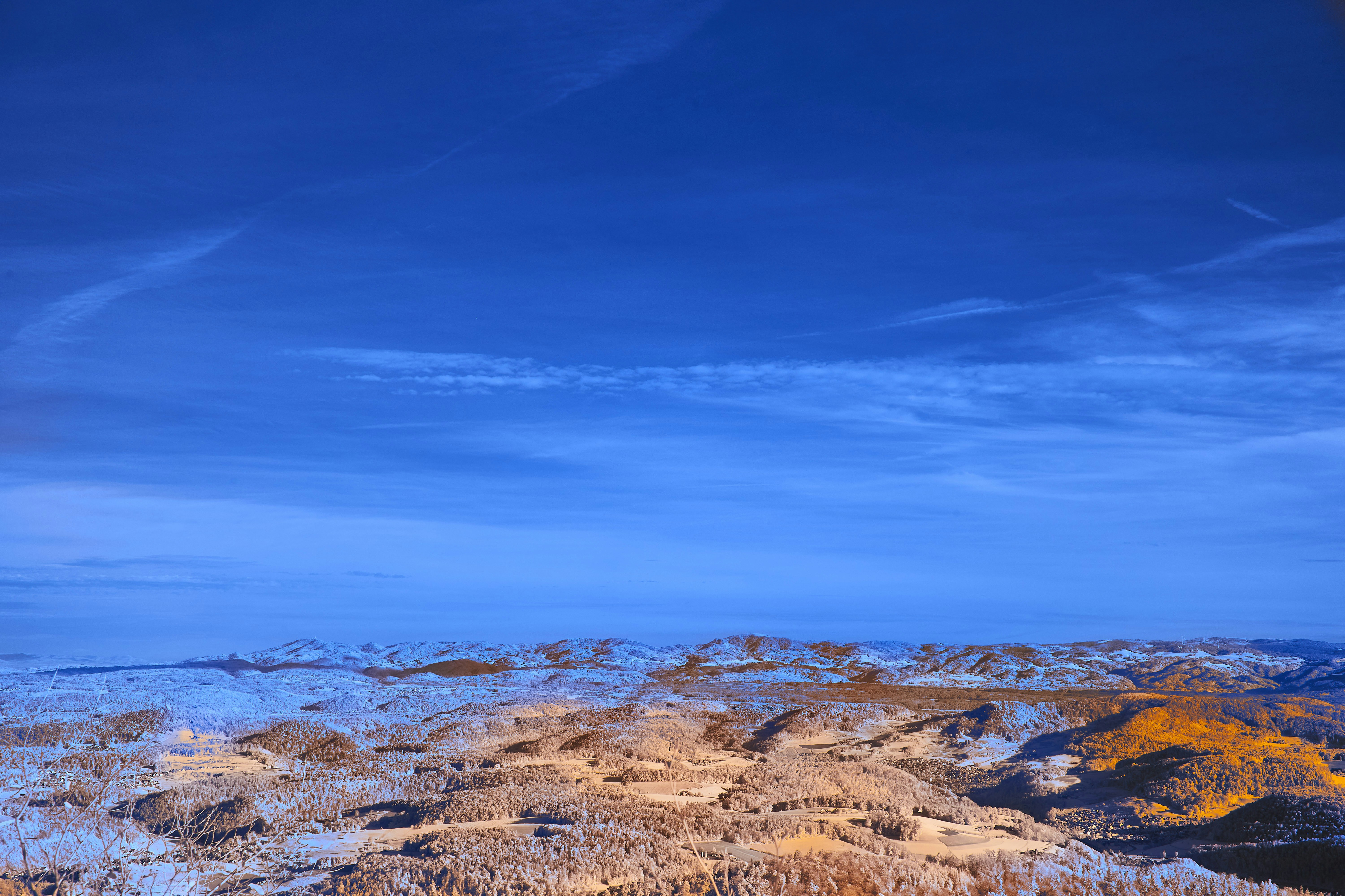 Un vasto cielo azzurro su un paesaggio colorato e ricco di texture.