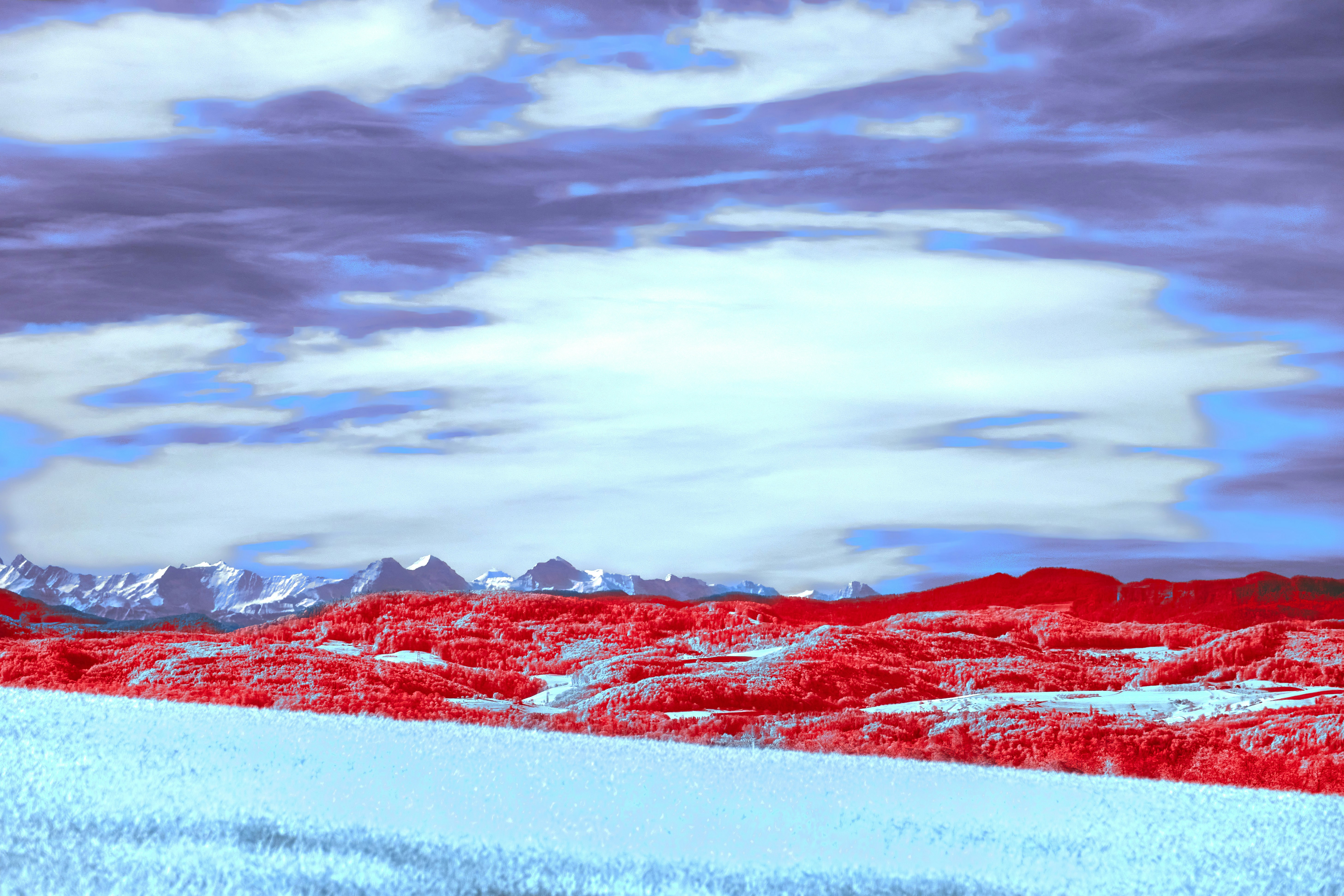 Paesaggio surreale con terreno rosso e montagne innevate
