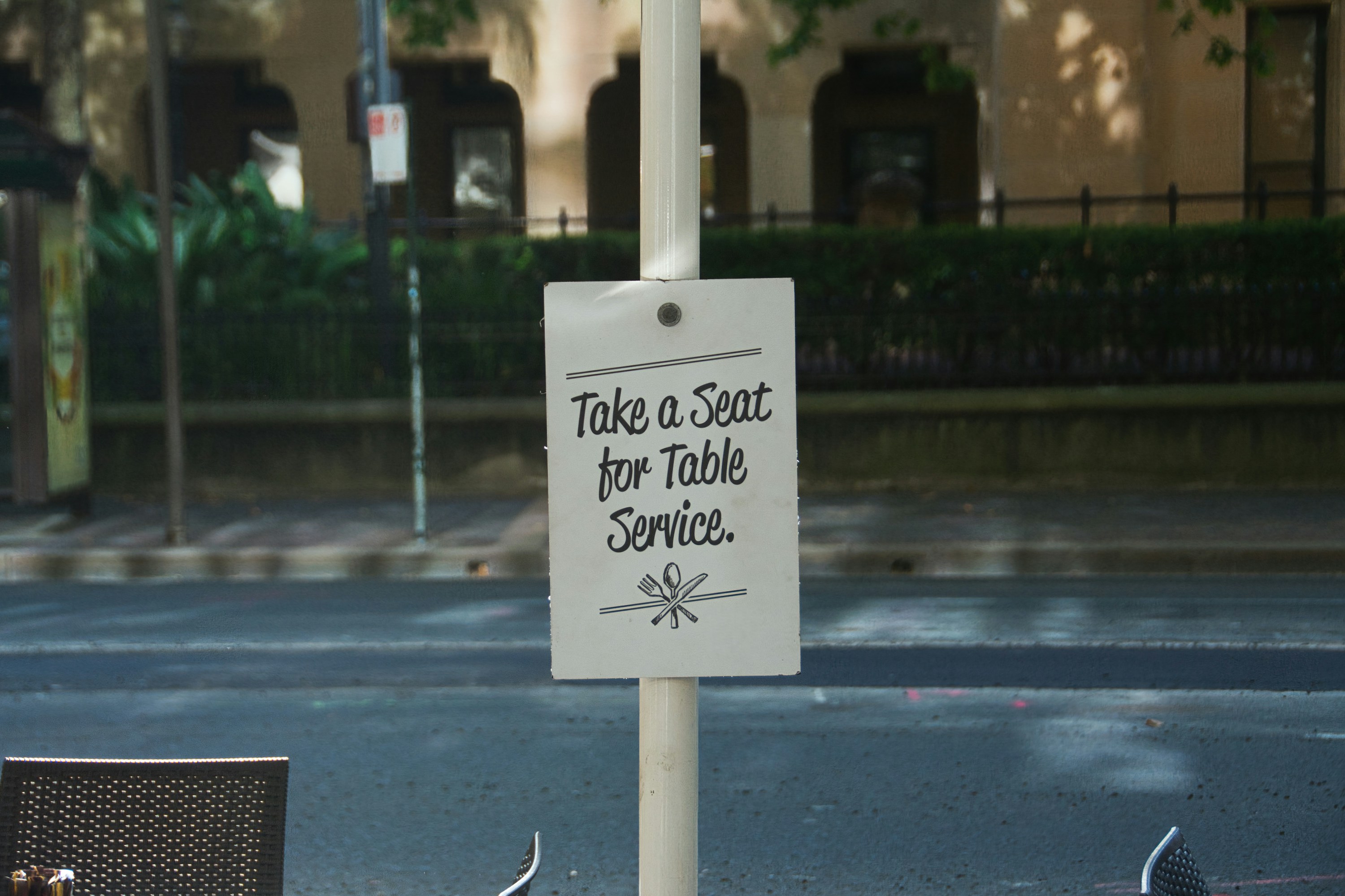 Sign reads take a seat for table service.
