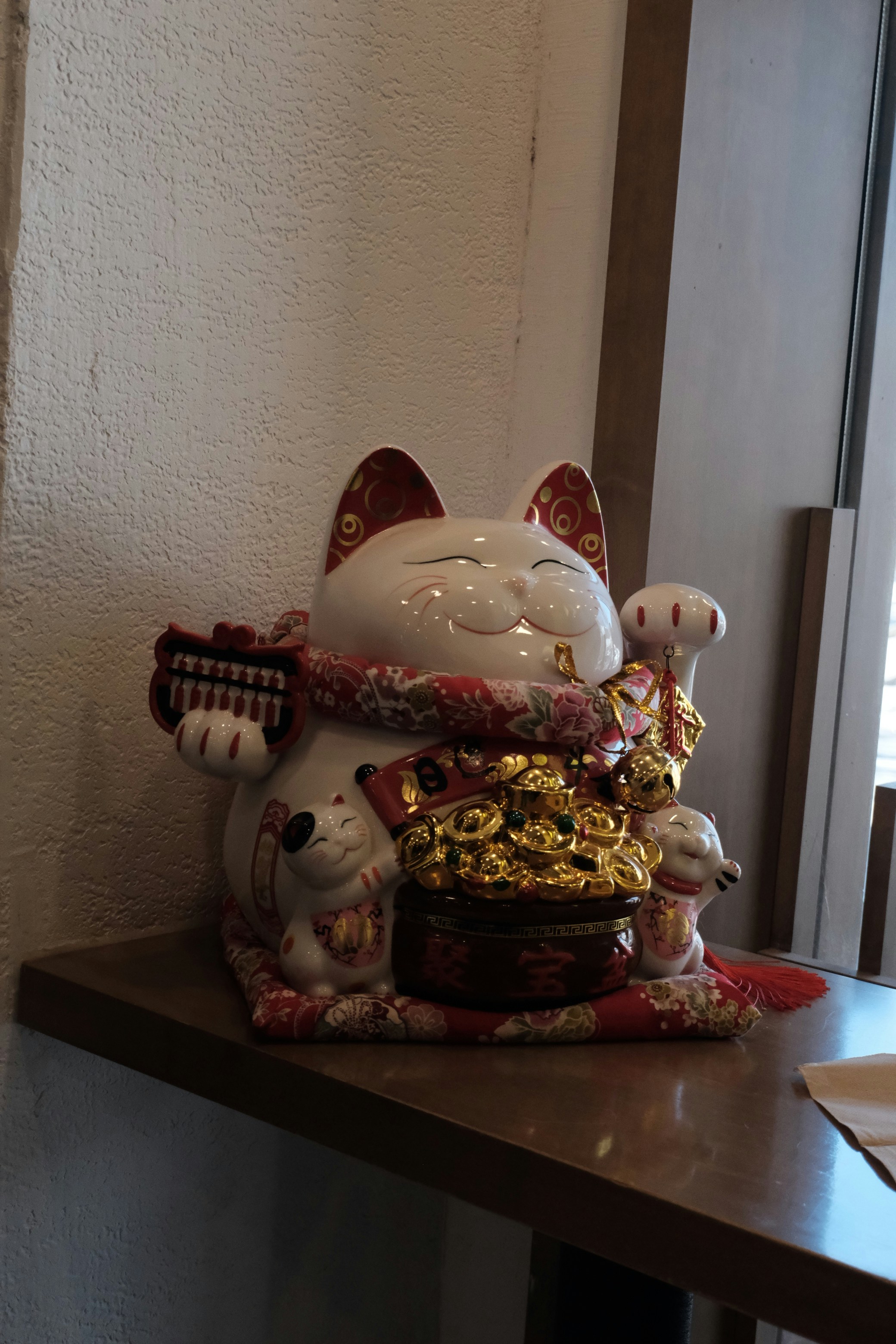 A white maneki-neko cat figurine with coins