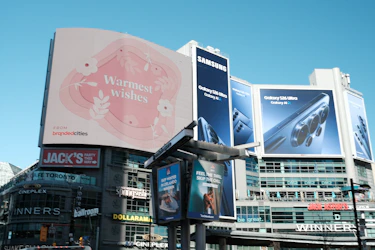 Large digital billboards display advertisements in a city.