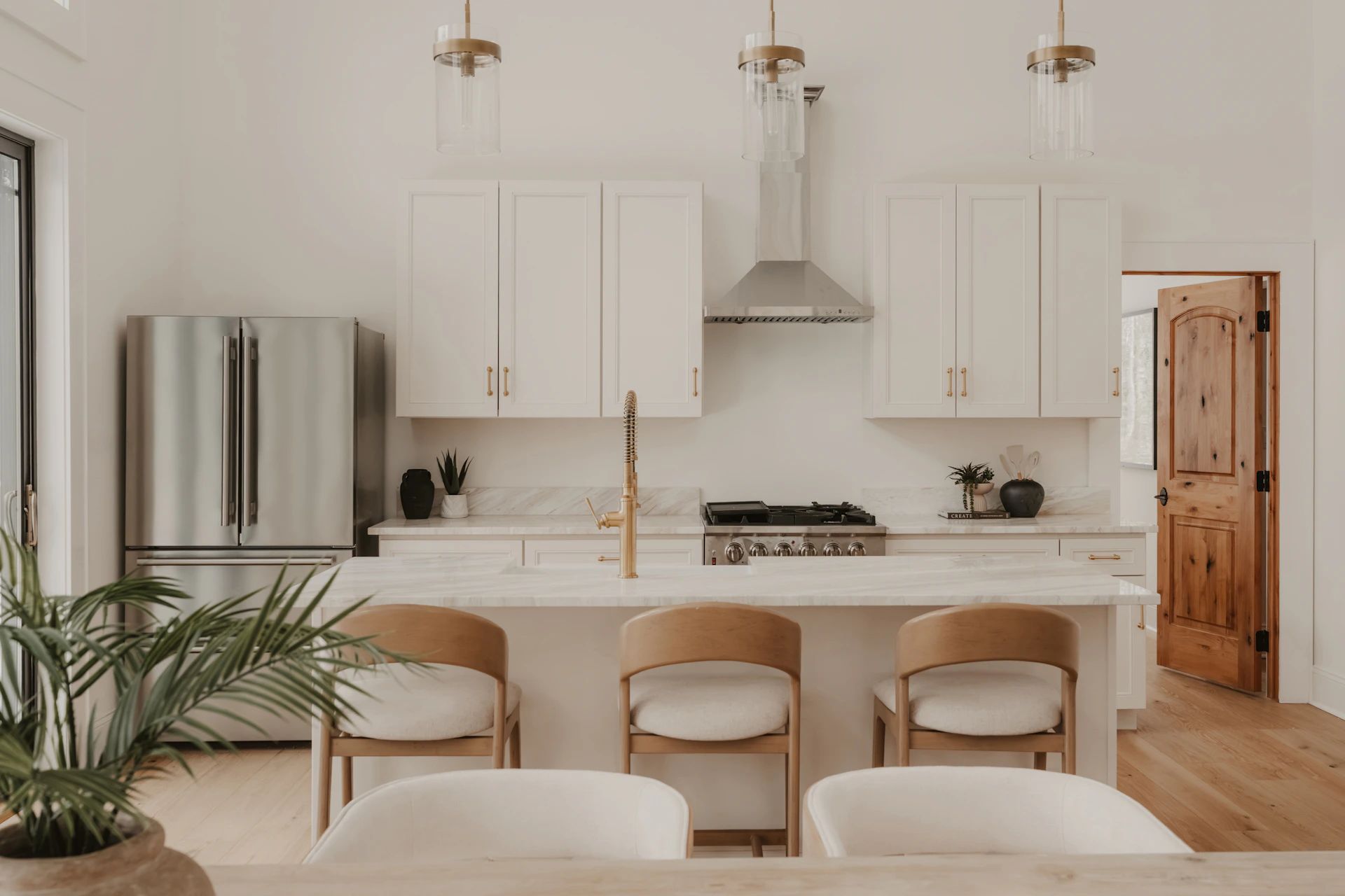 Modern white kitchen with stainless steel appliances and island.