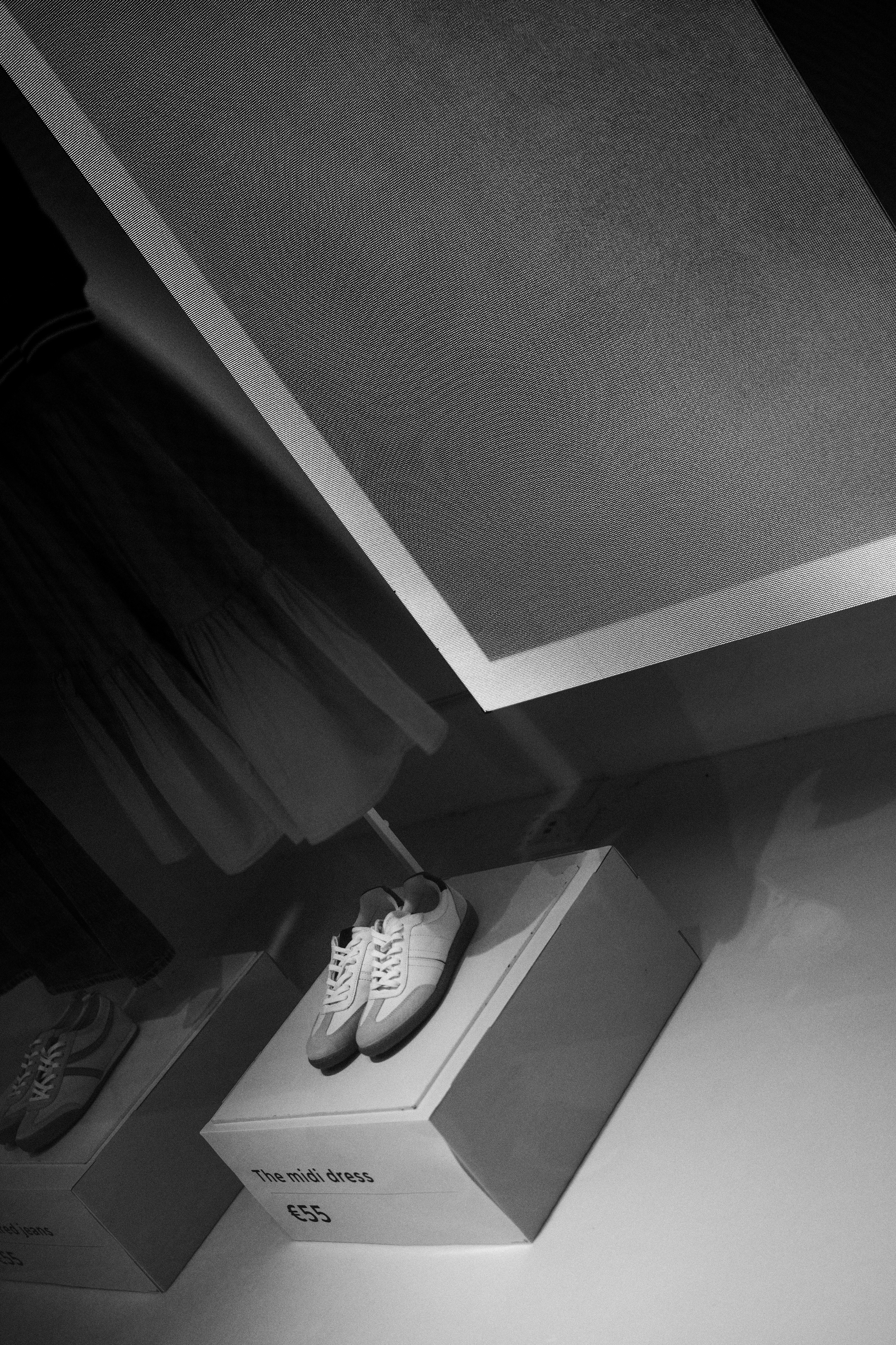 White sneakers displayed on white pedestals indoors.