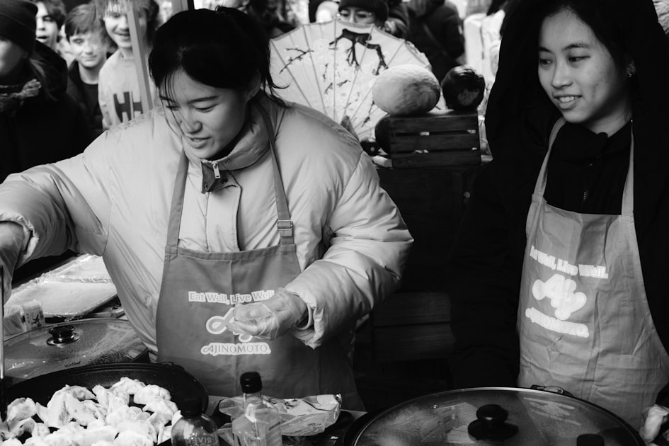 Two women preparing food at a market stall