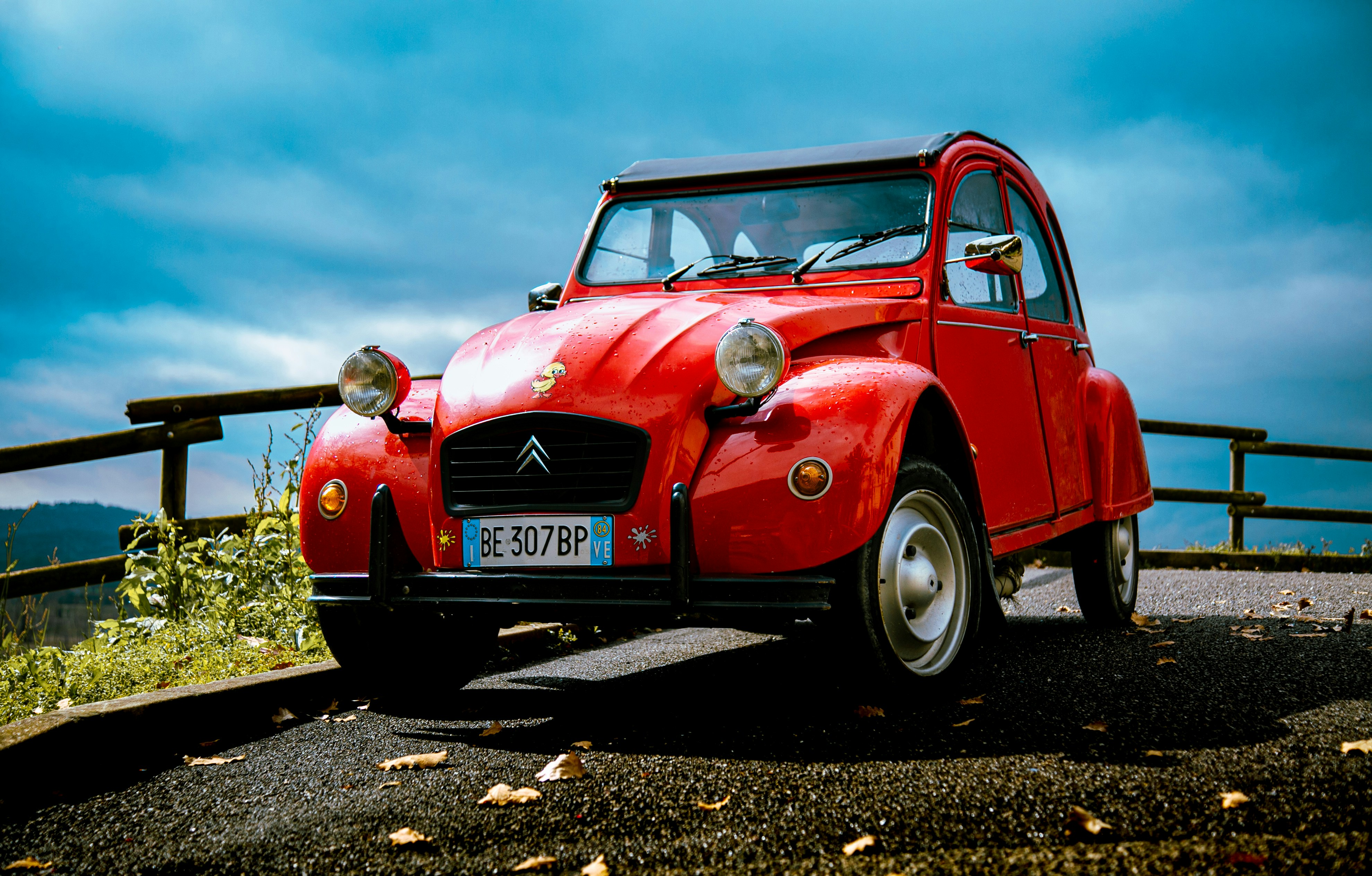 Ein klassischer roter Citroën 2 CV, der draußen geparkt ist.