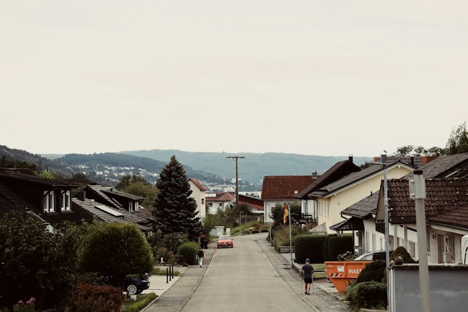 A suburban street lined with homes and distant hills, similar to the HOA communities in Summerlin and the southwest Las Vegas valley affected by the decorative grass fines