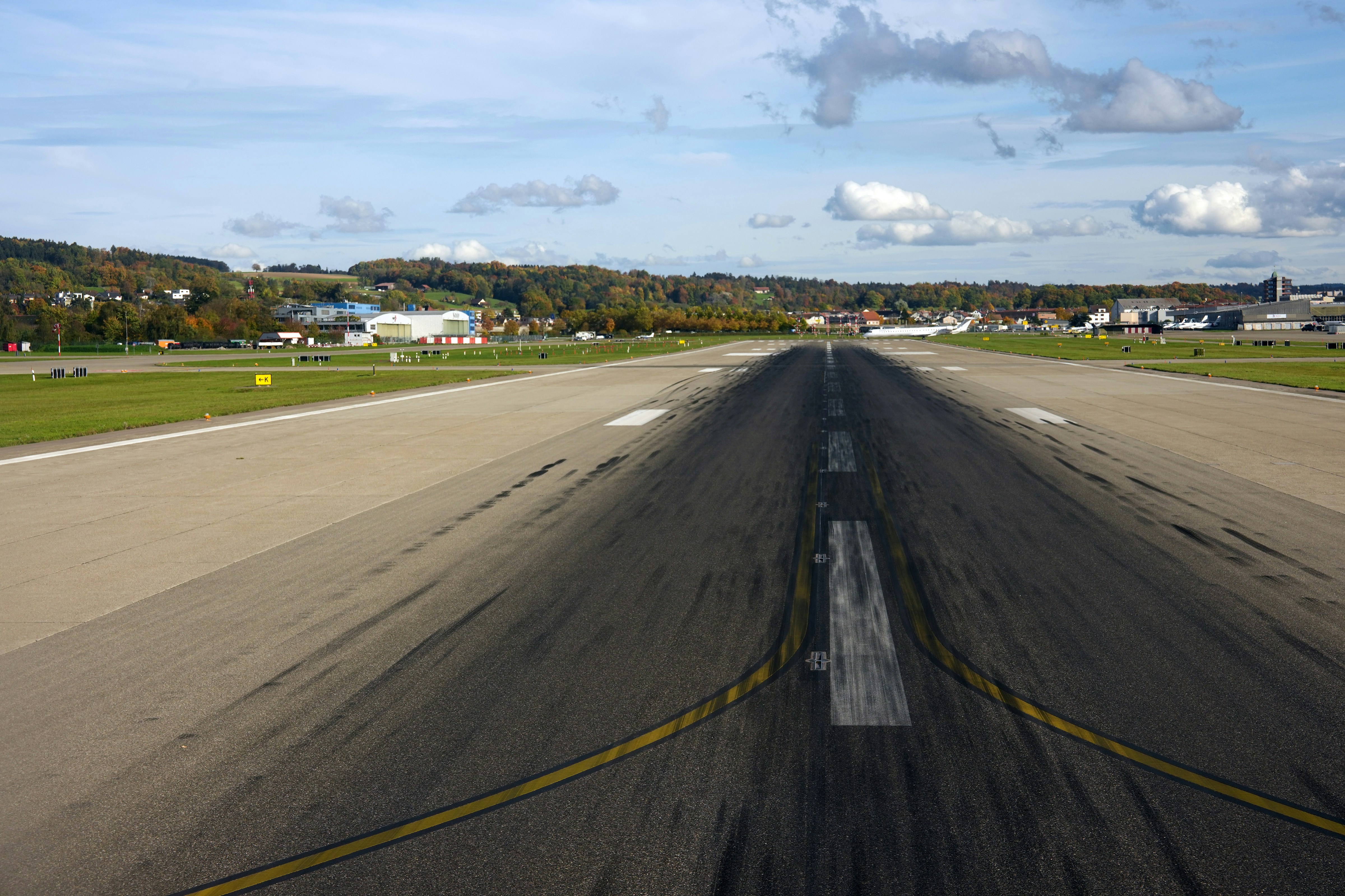 An empty airport runway with buildings in the distance.