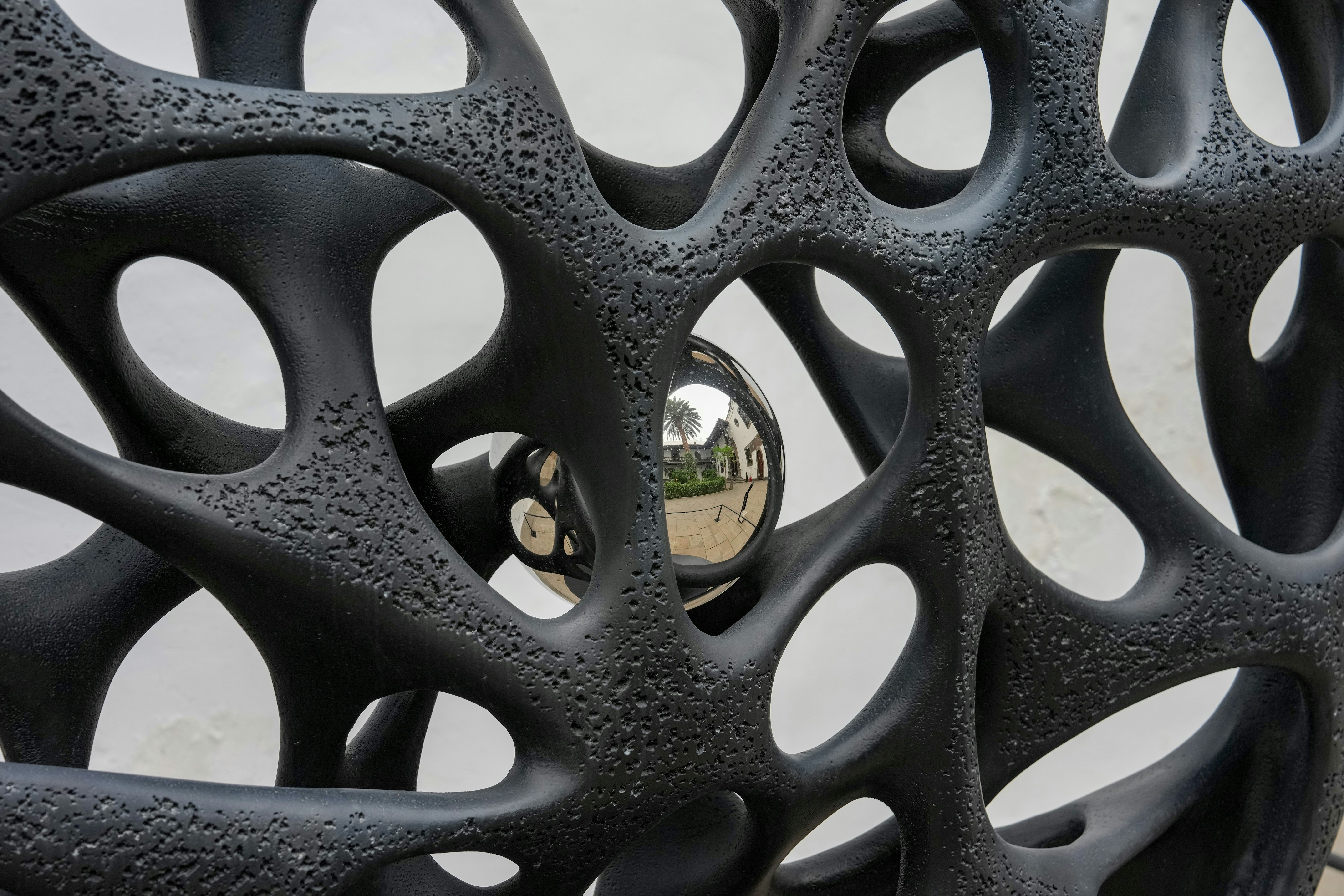 Abstract black sculpture with a reflective sphere inside.