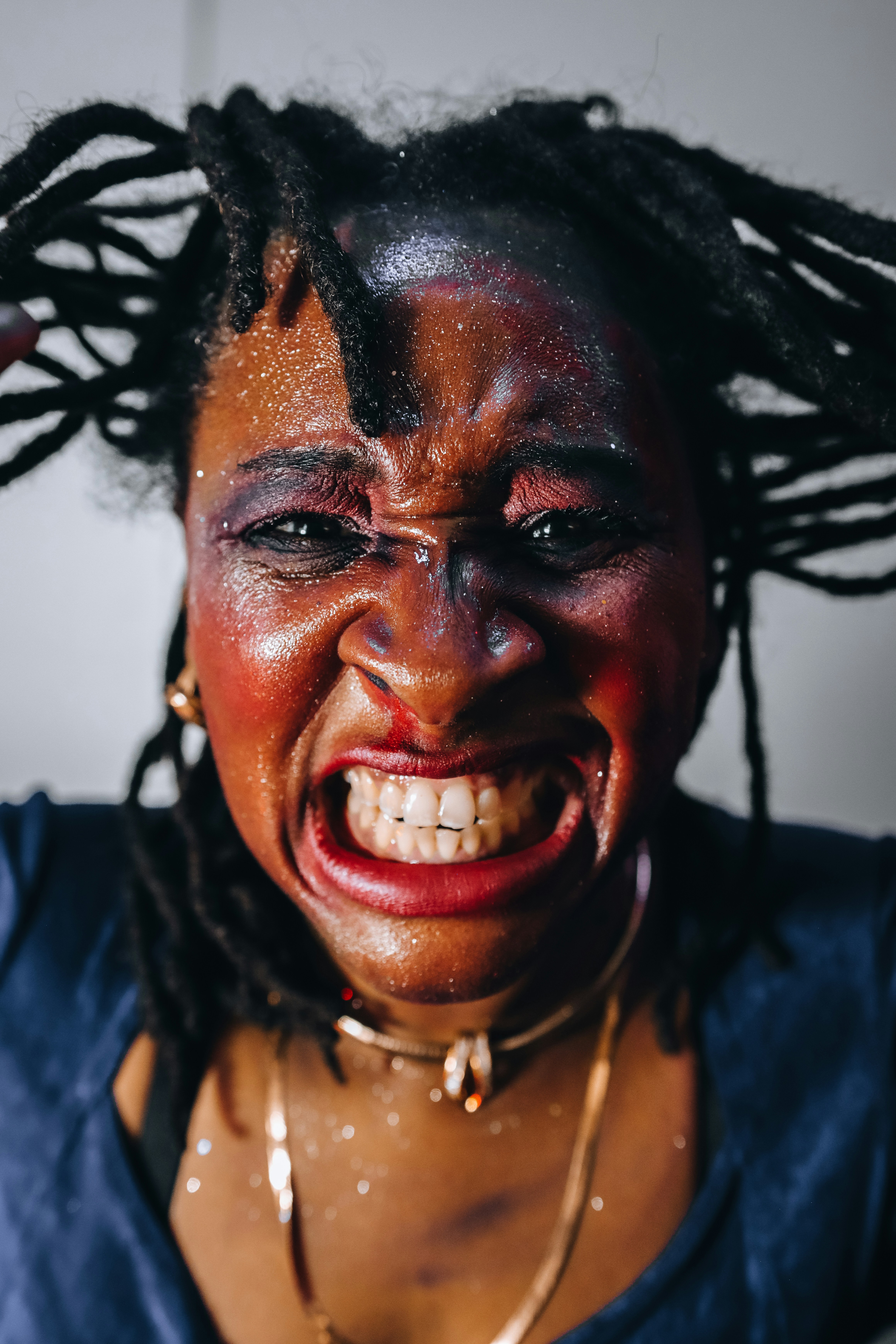 Mujer con maquillaje de purpurina hace muecas con las manos en el pelo